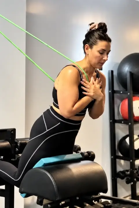 Woman performing a resistance exercise with a trainer.
