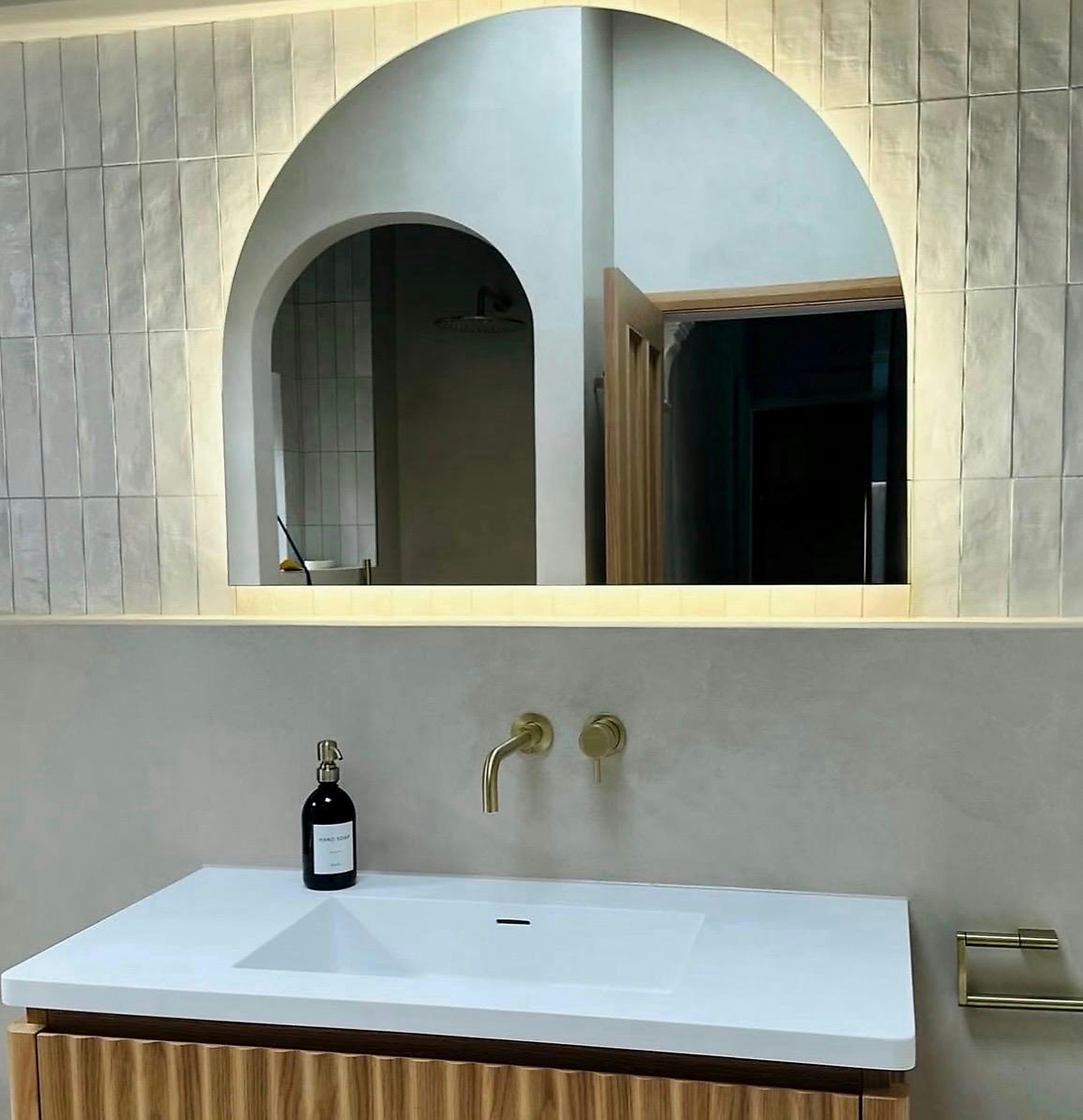 Bathroom basin beneath an arched mirror