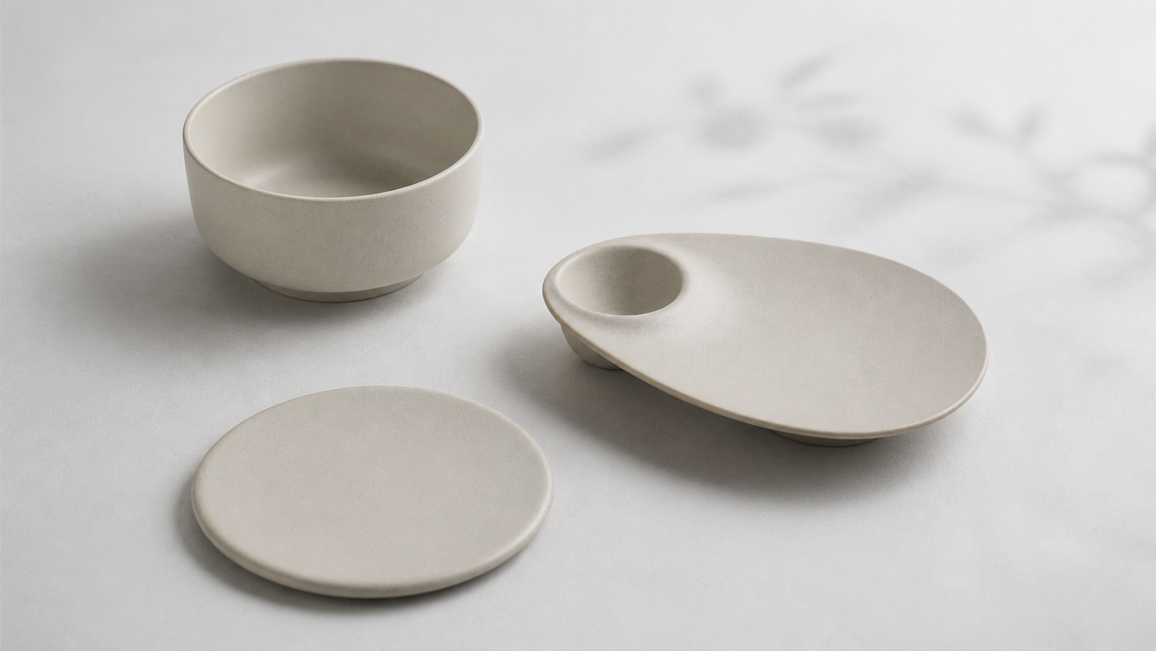 A coordinated Quiet Geometry bowl, flat plate and serving platter in soft natural light
