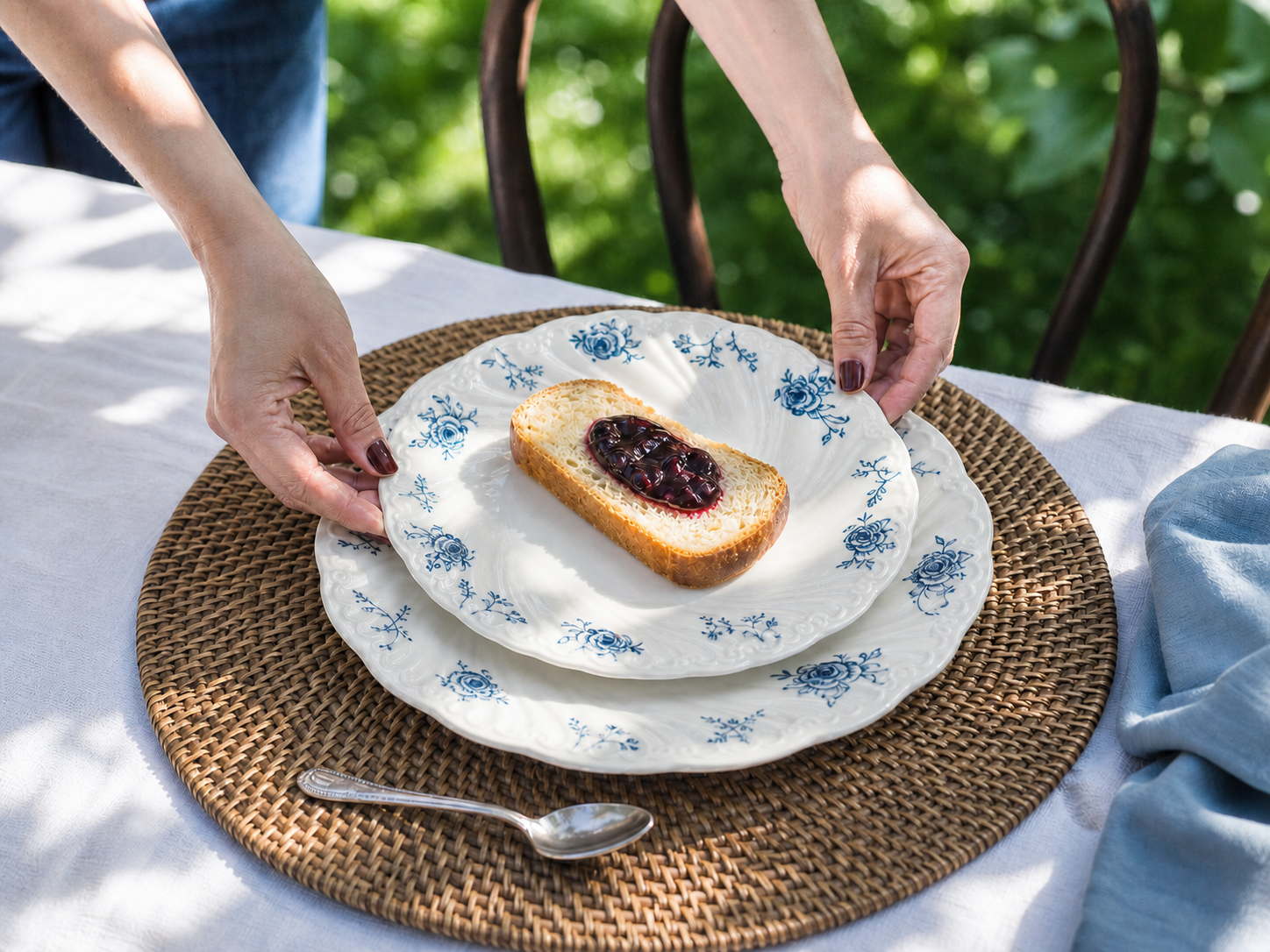 Hands placing layered Ivory Lace blue rose plates at a garden table