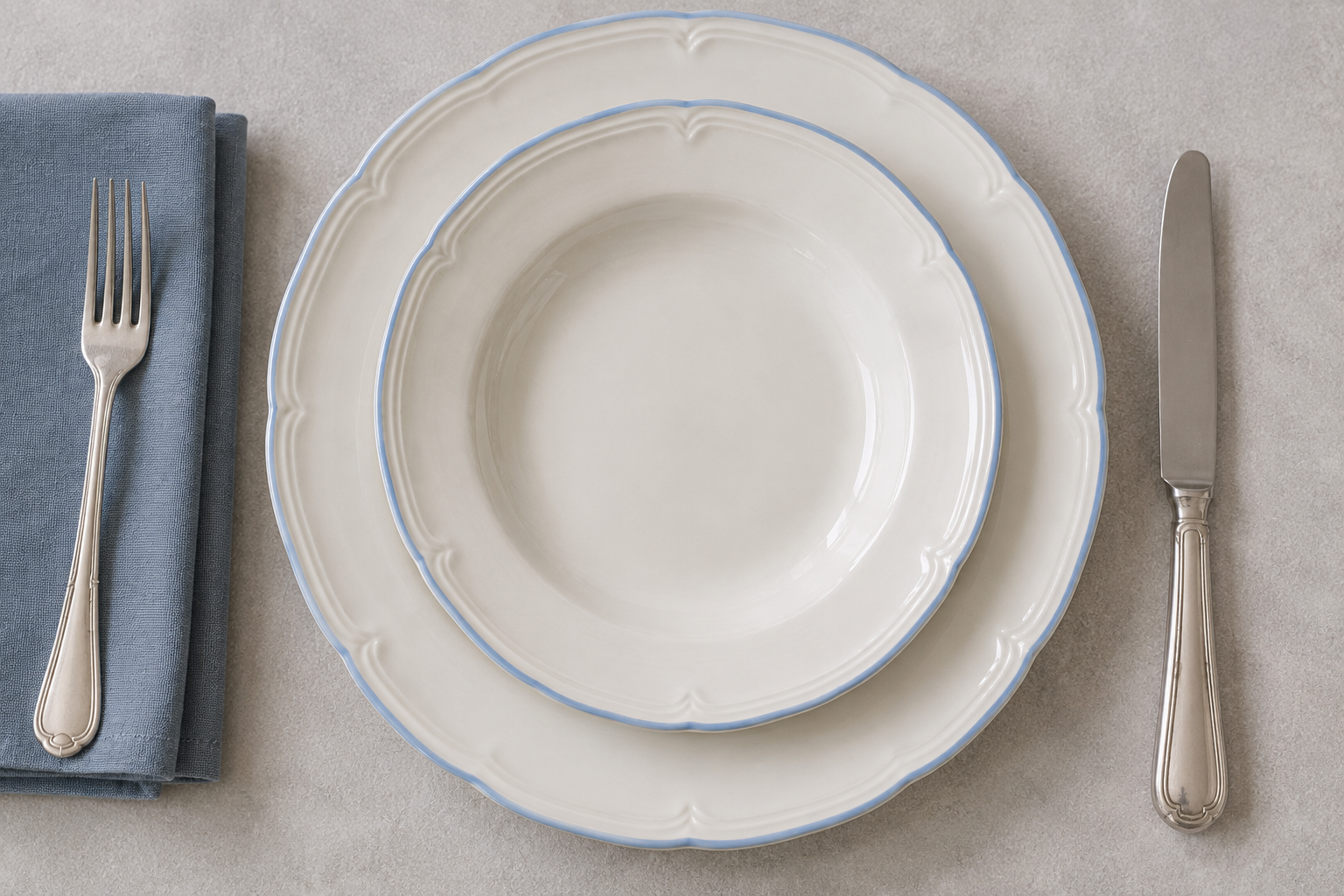 Overhead Meadow Sprig plate setting with scalloped blue rims and silver cutlery