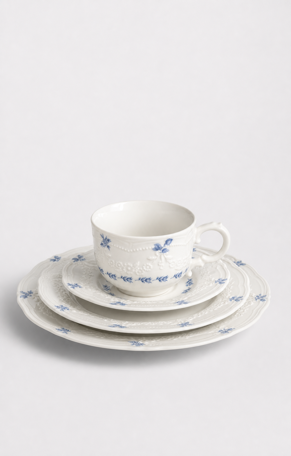 User-selected Willow Lace hero: blue-floral tea cup and saucer with a complete stack of relief-edged plates