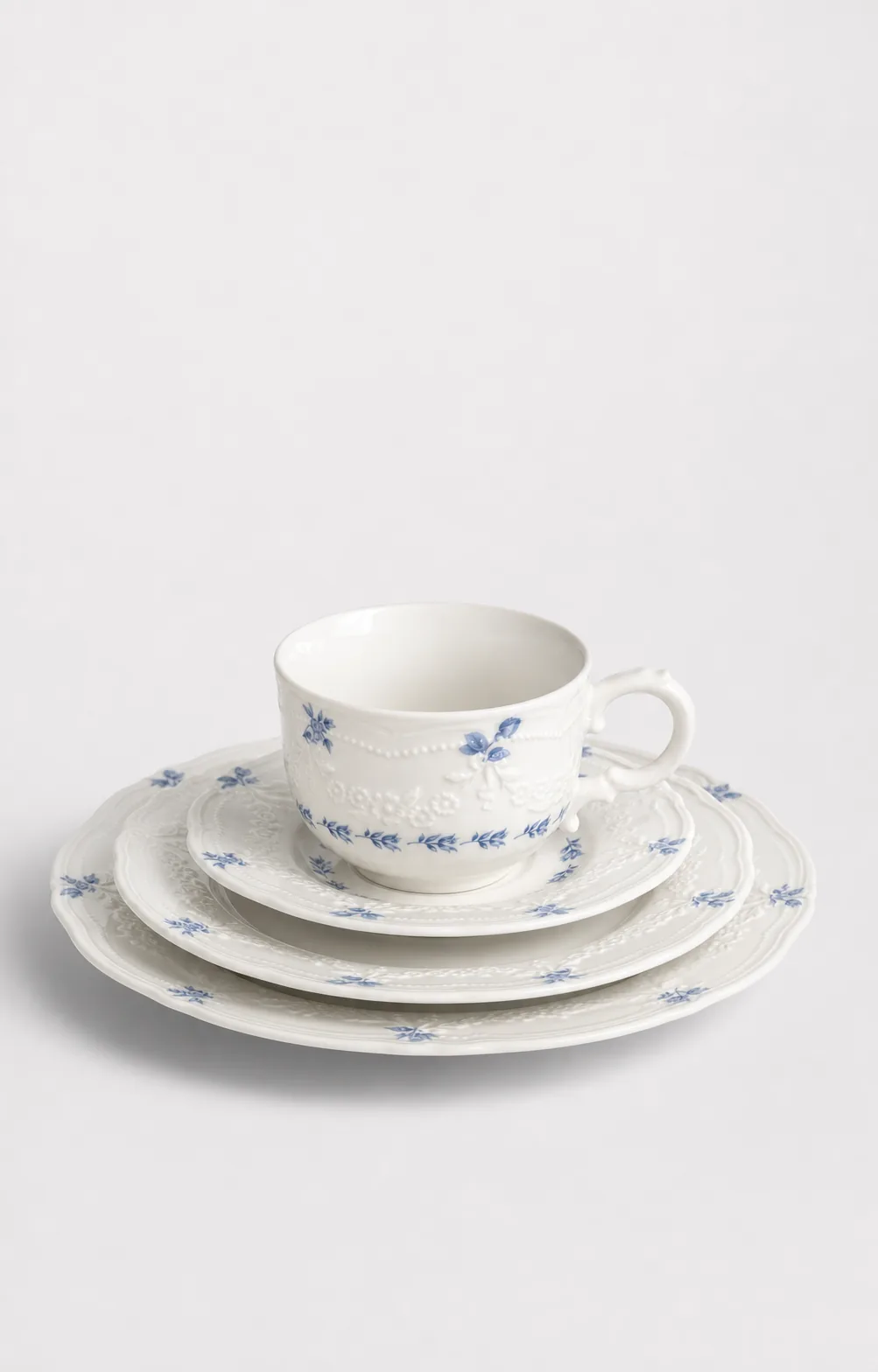 User-selected Willow Lace hero: blue-floral tea cup and saucer with a complete stack of relief-edged plates