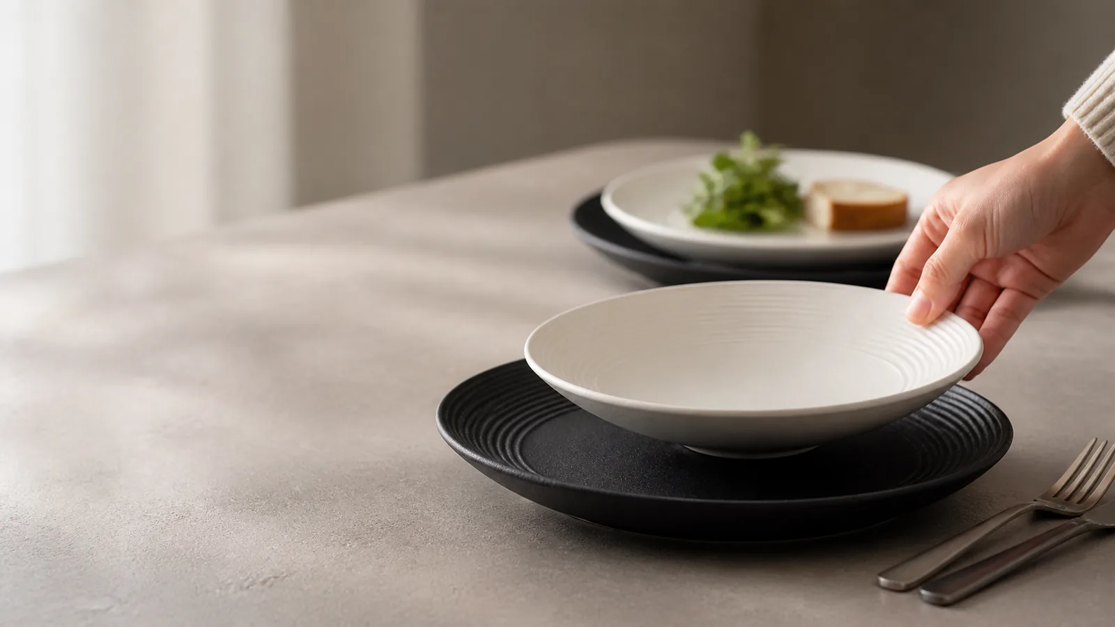 Concentric Ridge white bowl and black plates in a warm breakfast setting