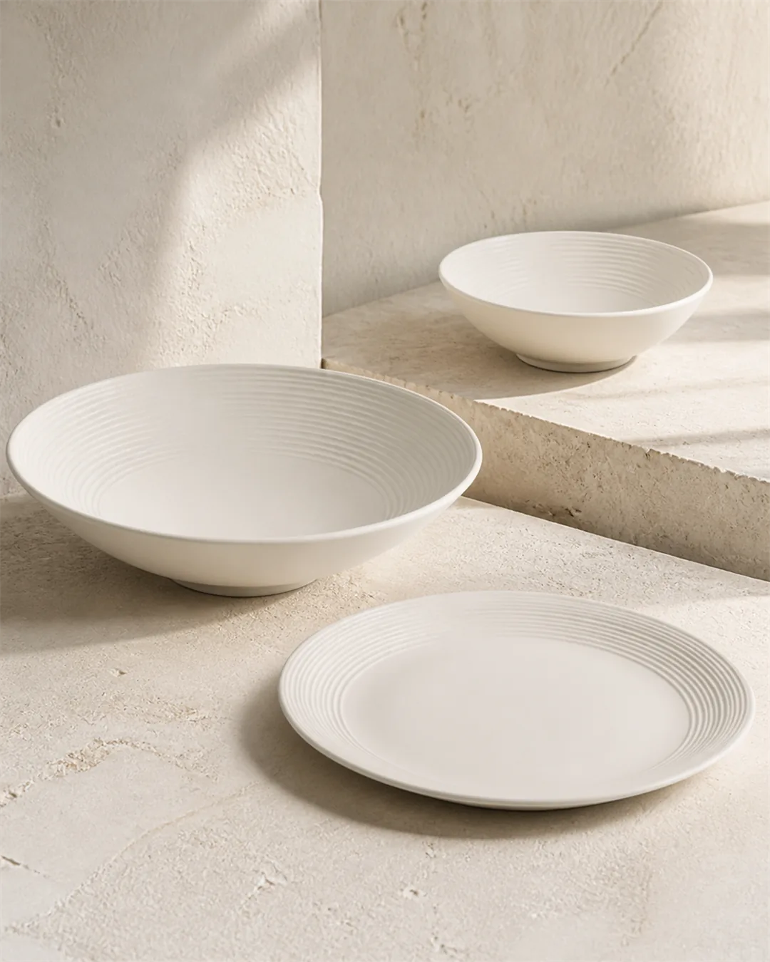 Concentric Ridge white plates and bowls arranged as one coordinated family