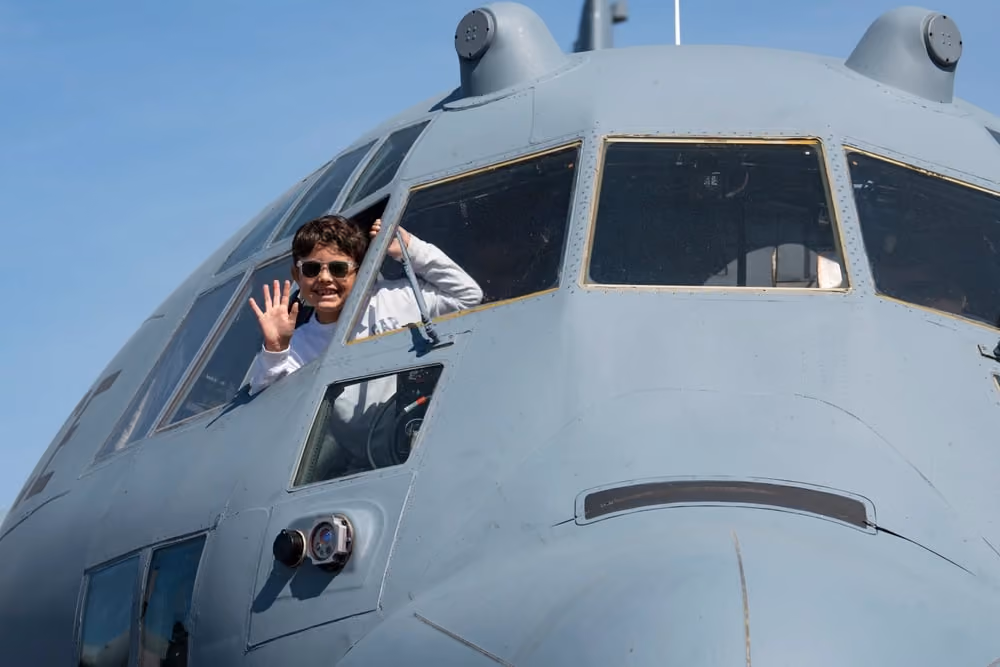 child waving out window of plane cockpit