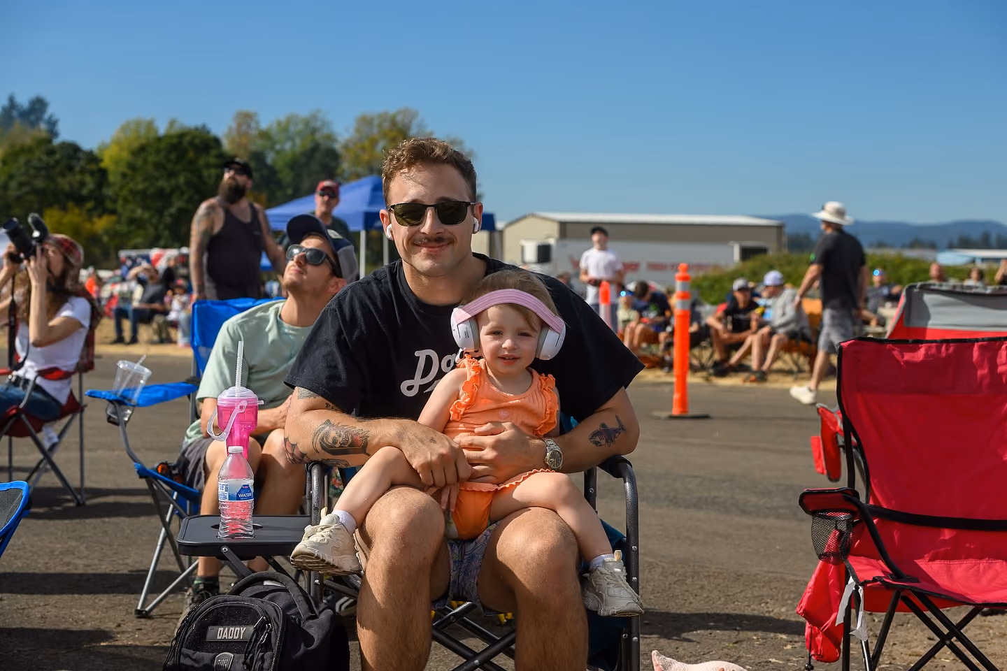 child sitting on man's lap watching air show