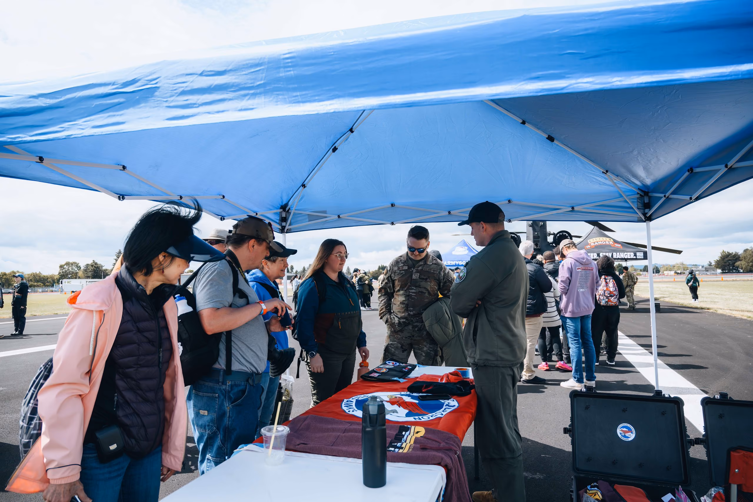 group of people gathered under blue tent on tarmac