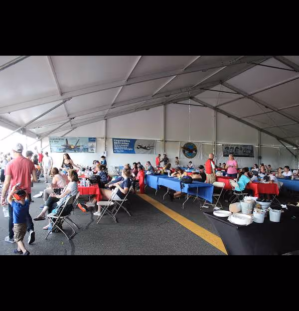 group of people gathered under large tent at air show