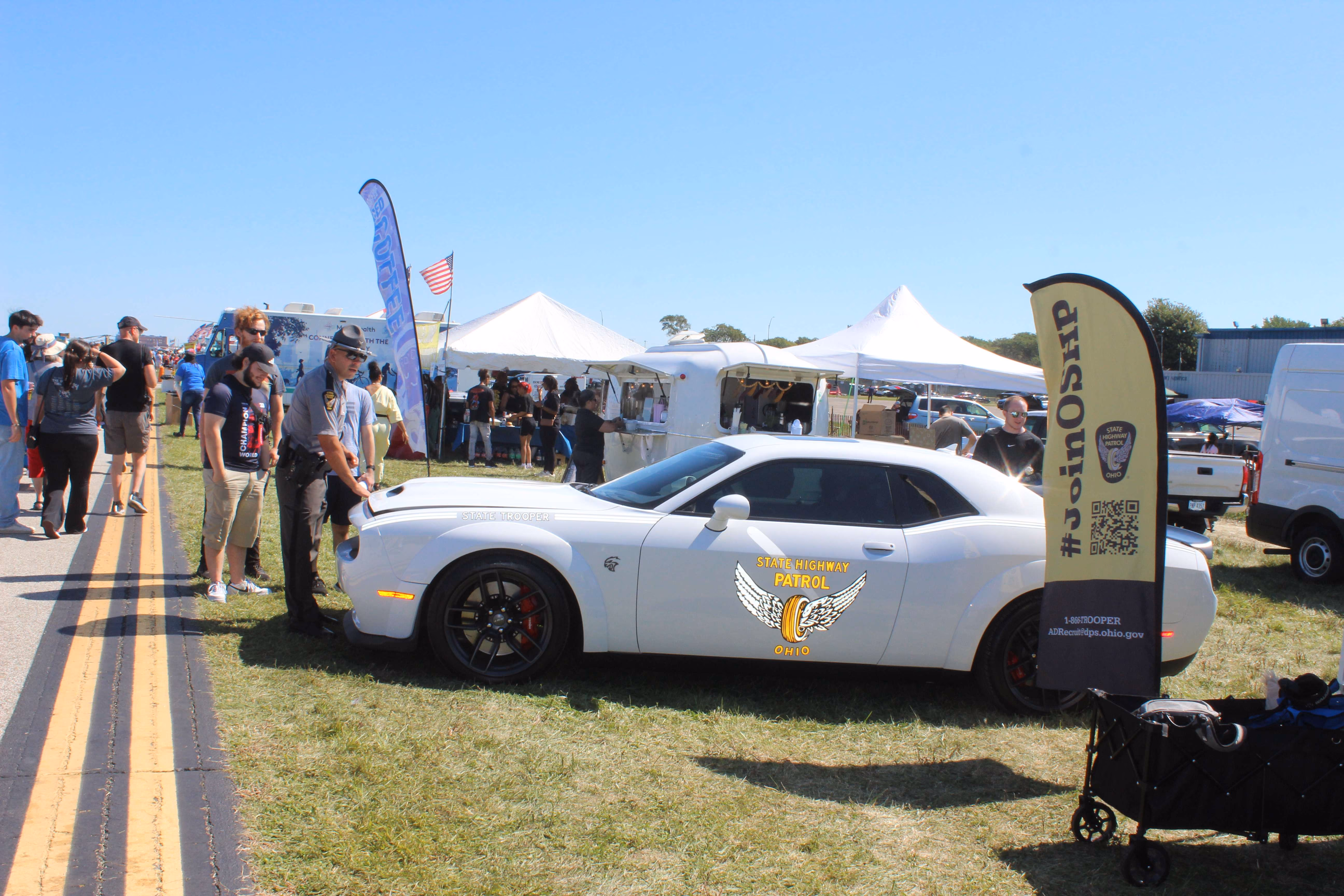 Trooper with trooper vehicle in front of marketing tents