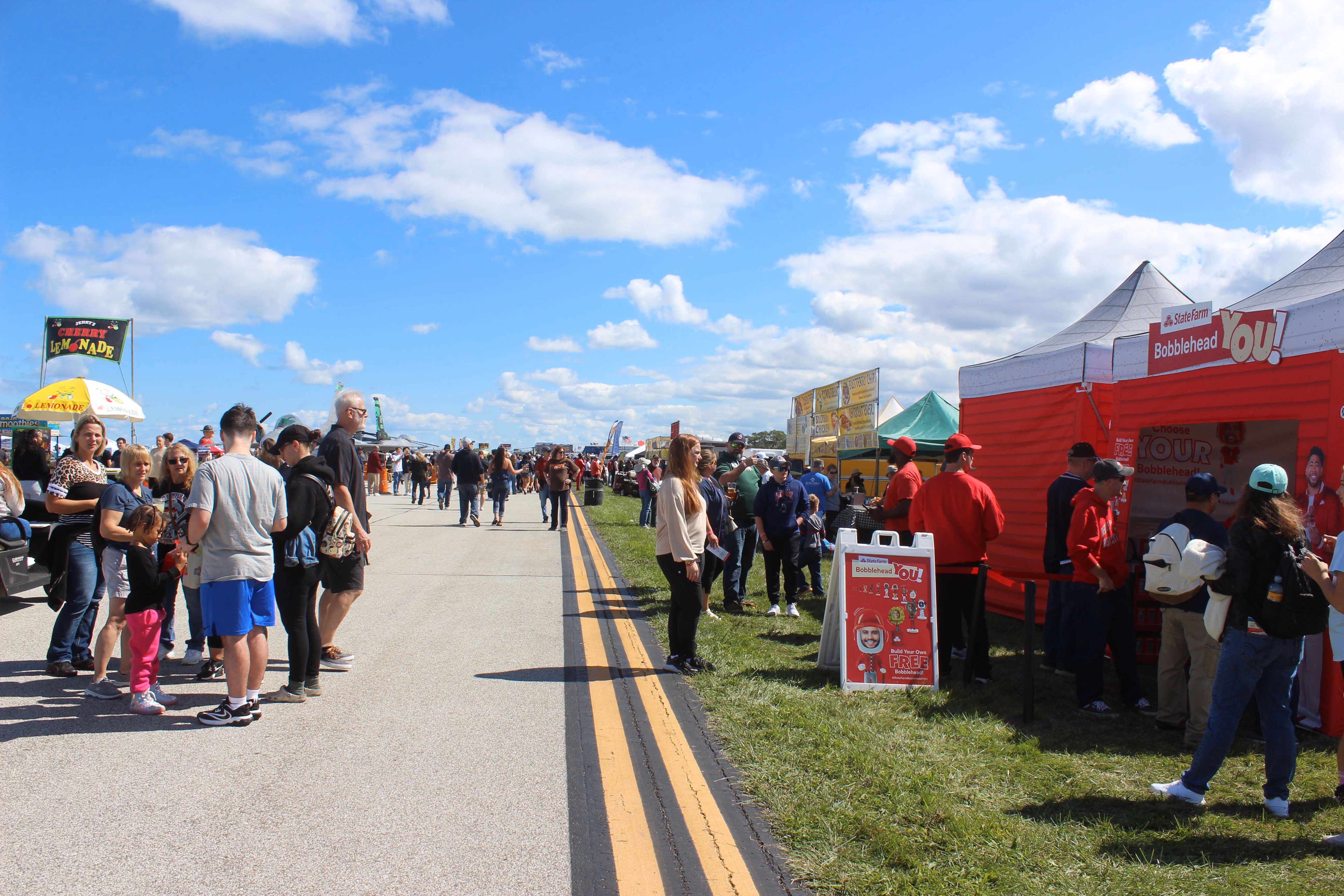 marketing tents next to air show runway with people walking around
