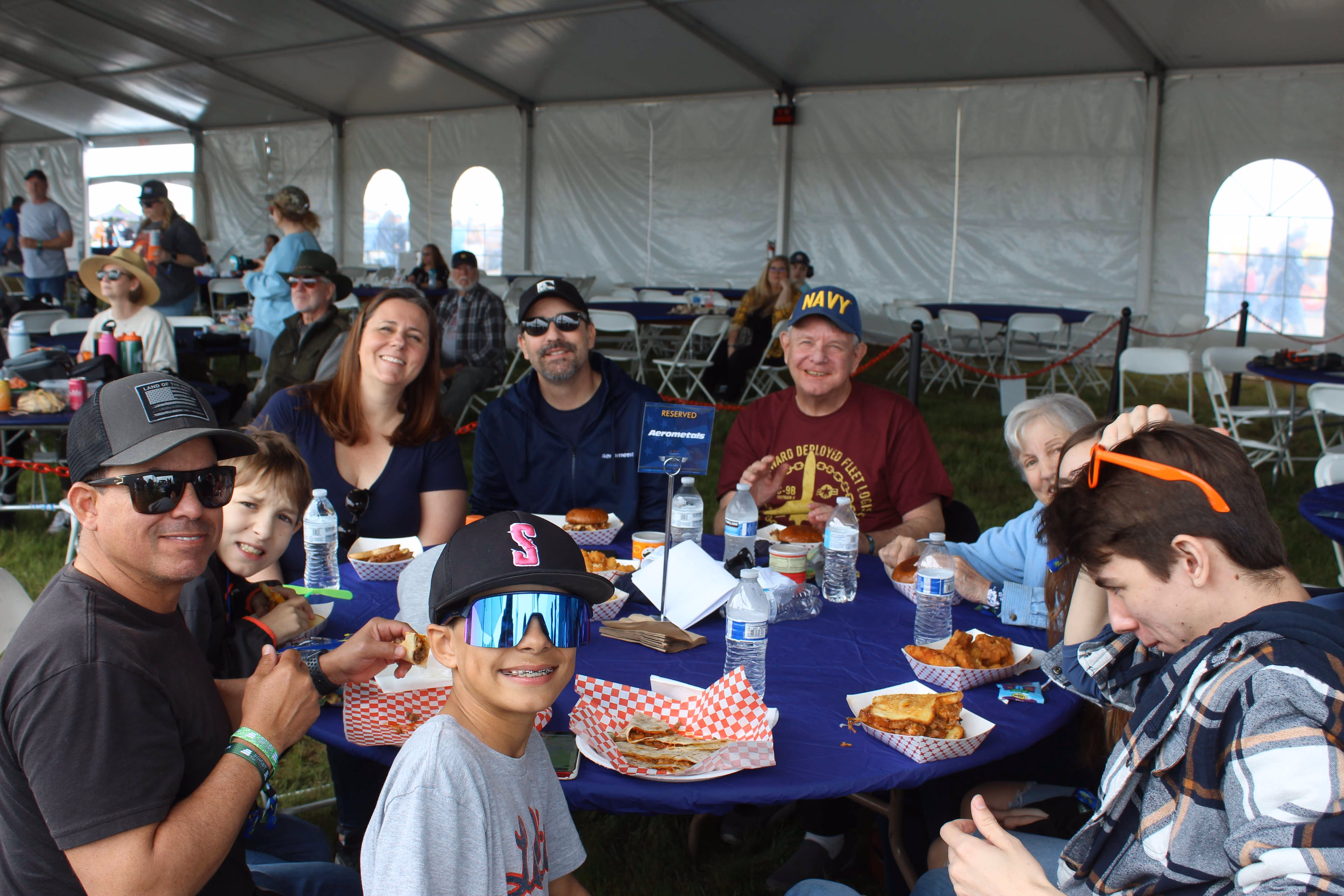 group of people eating at table under tent