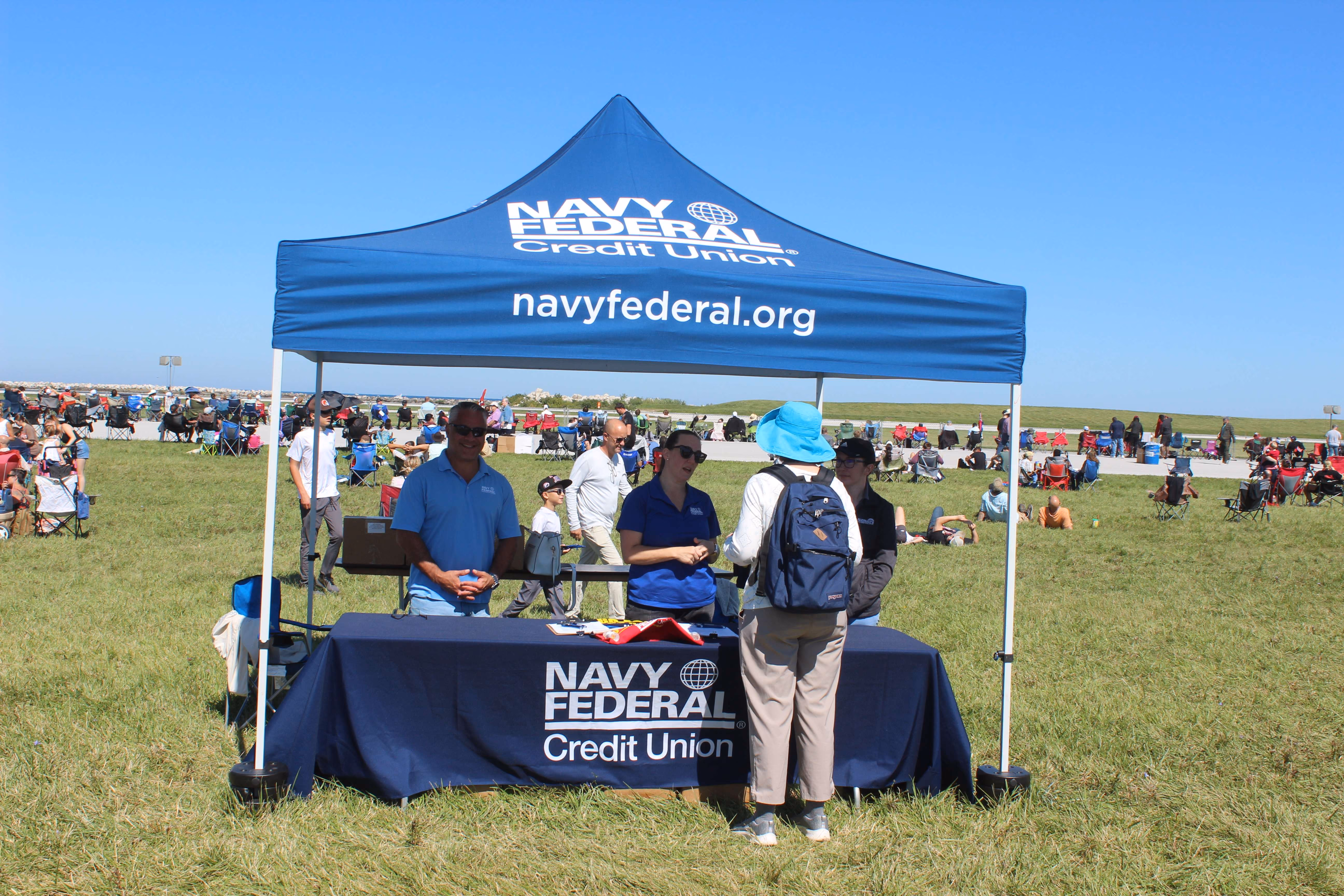 navy marketing tent and table with small group of people
