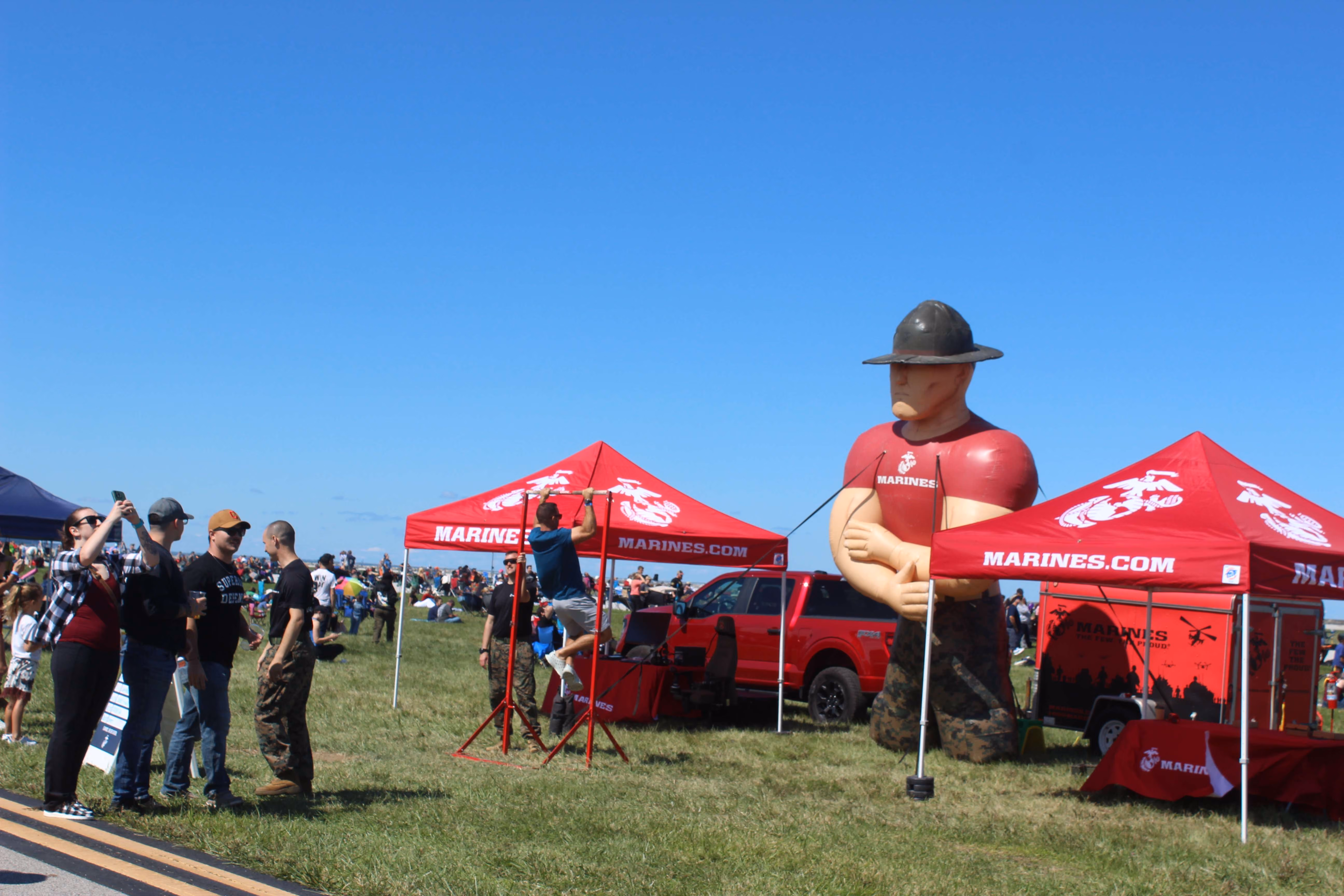 two red tents with inflatable marketing mascot in a field