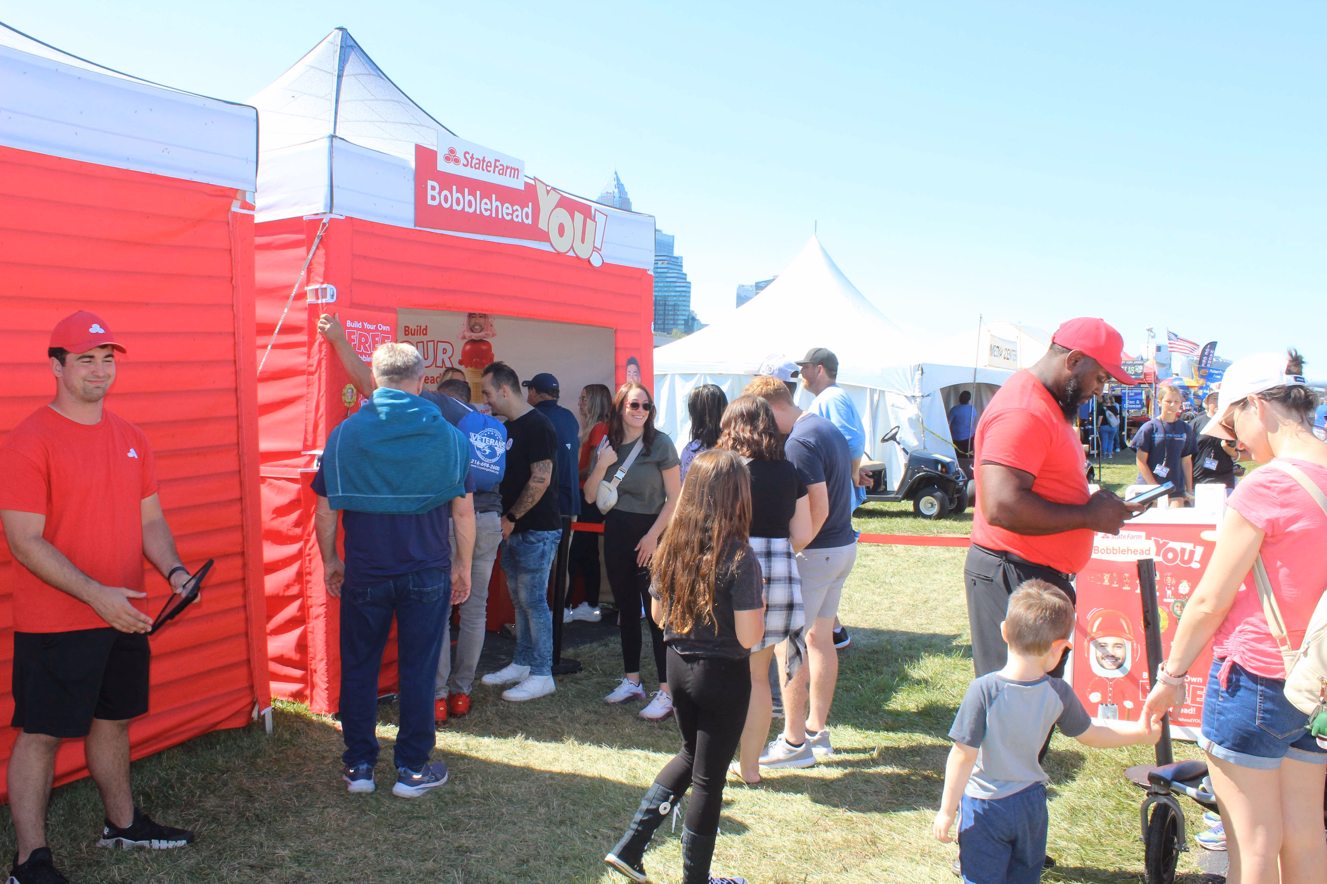 group of people gathered in front of red and white marketing tent at air show