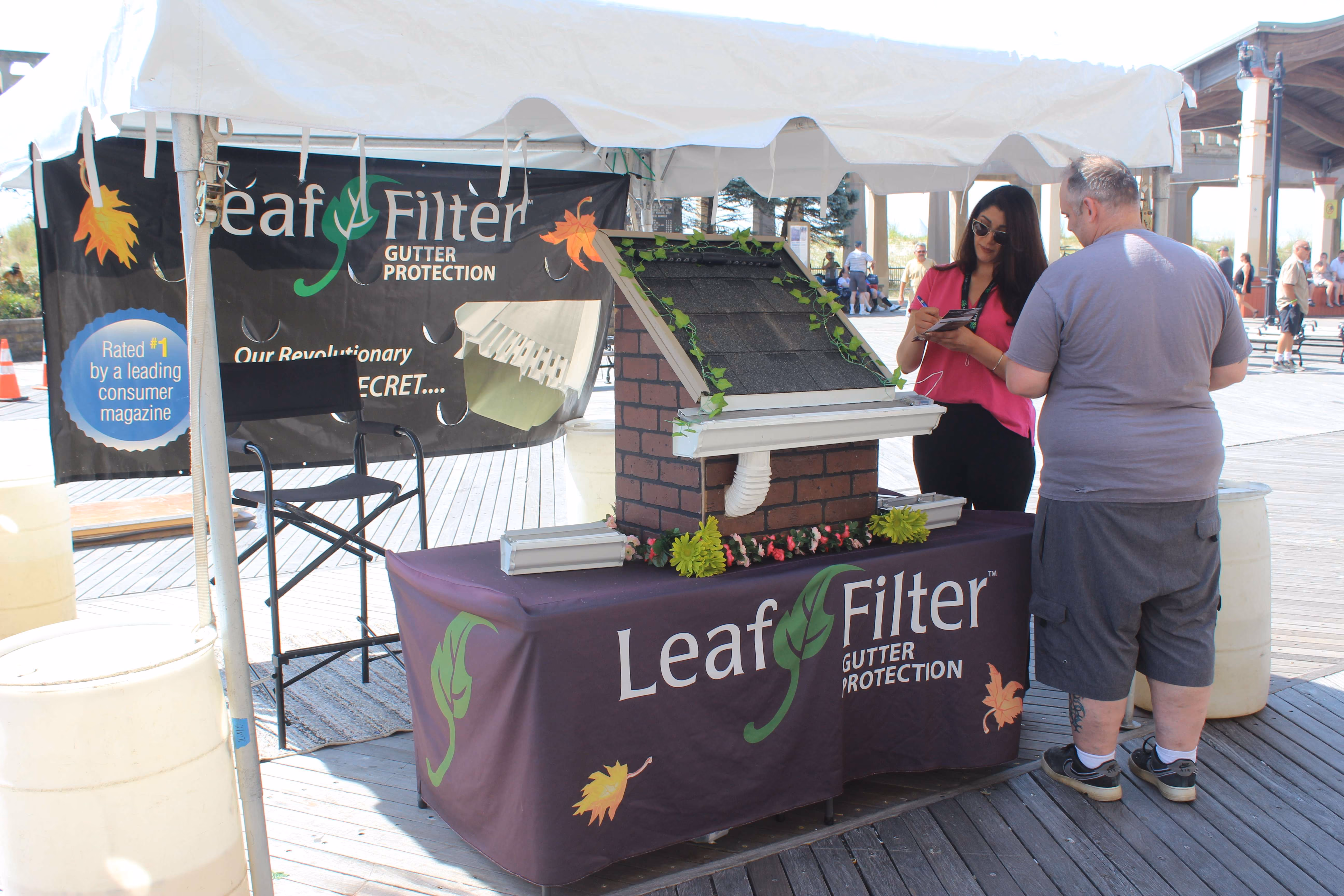 two people under white marketing tent observing leaf filter demonstration