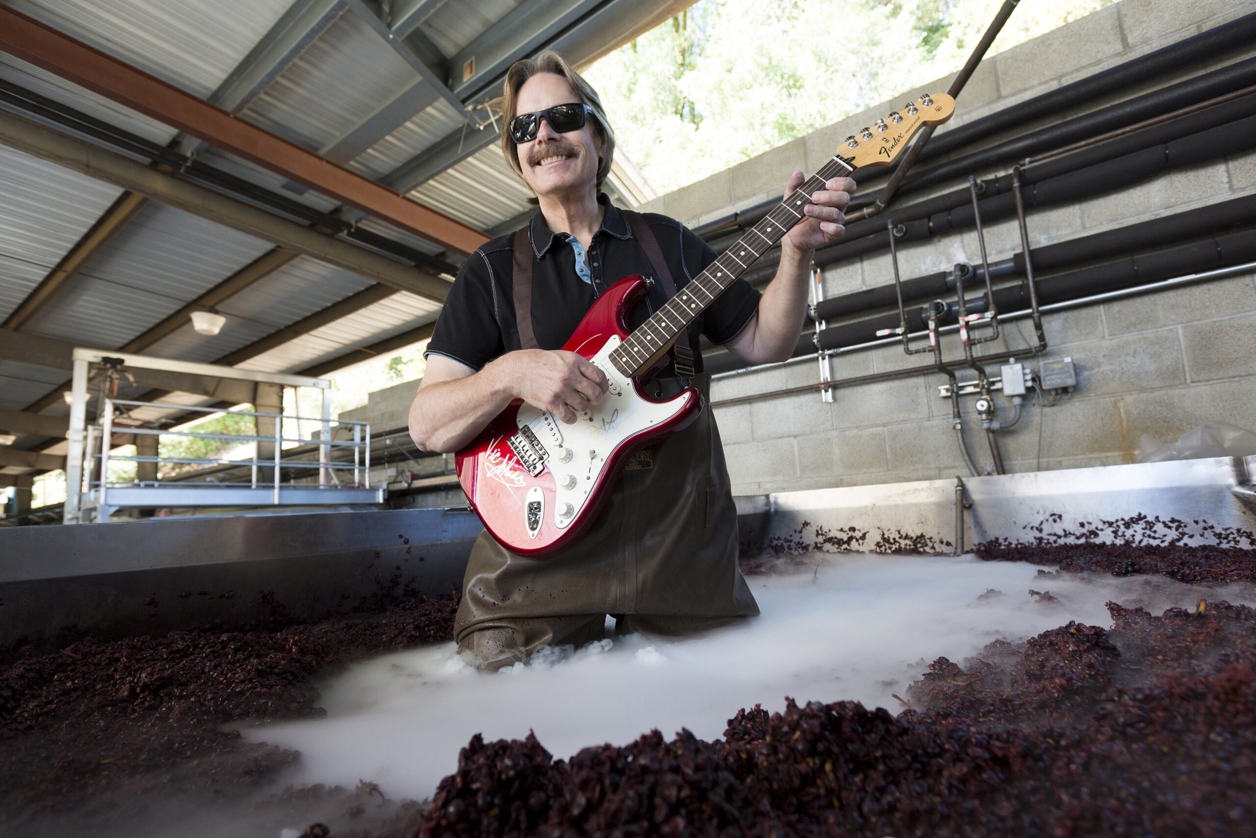 Bob Cabral, winemaker at Bob Cabral Wines, playing guitar in a fermentation tank during harvest