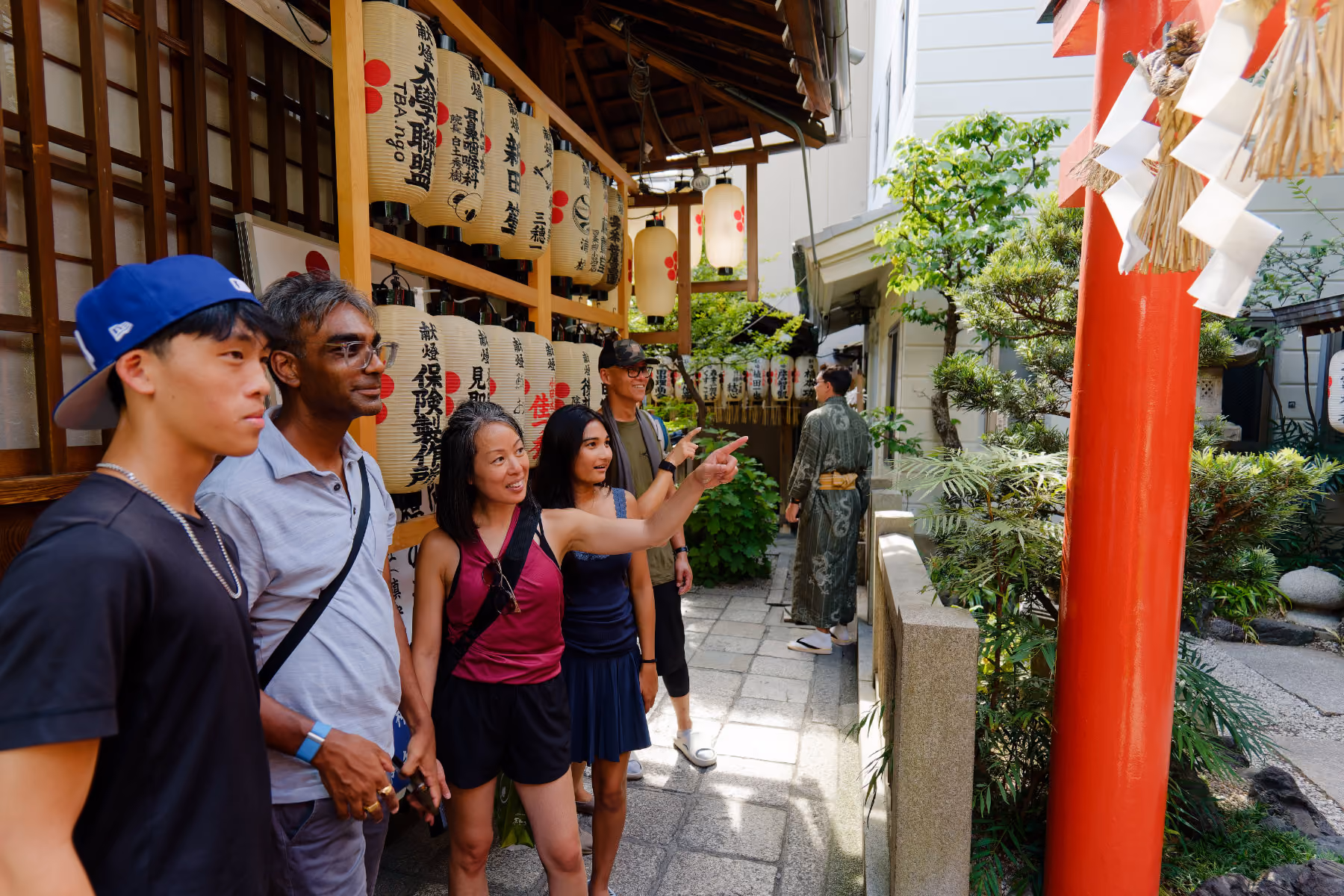 Small group on a private Kyoto walking tour discovering a quiet shrine with a local guide pointing at shrine details.