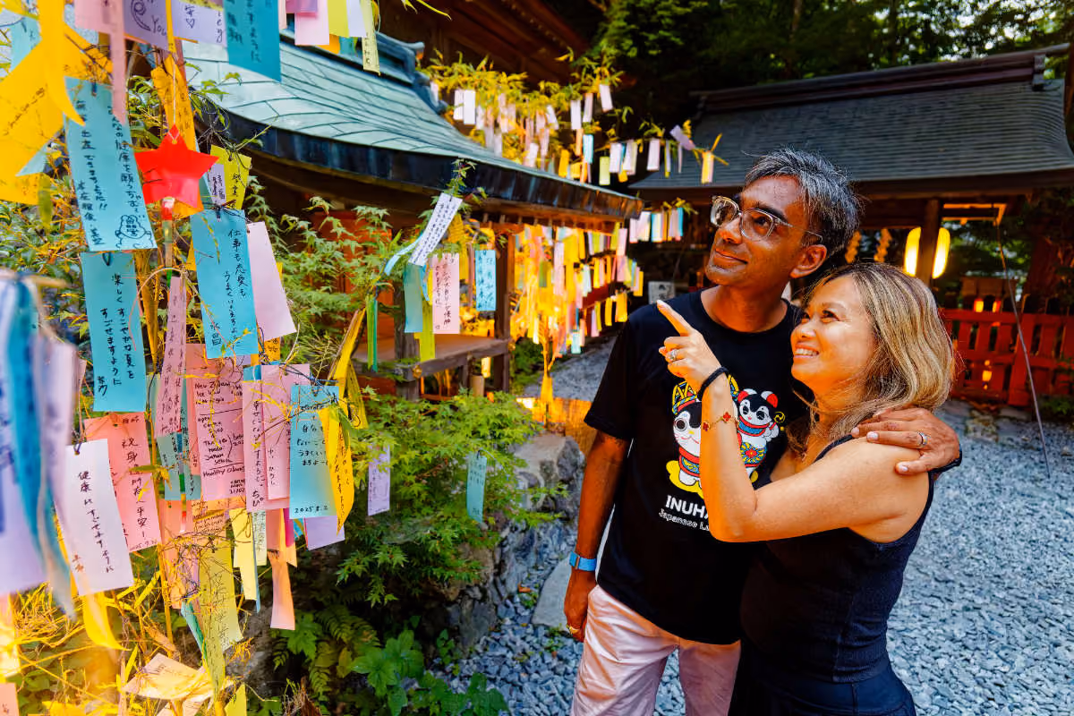 Couple admires colorful wish strips hanging on bamboo branches at a Japanese festival.