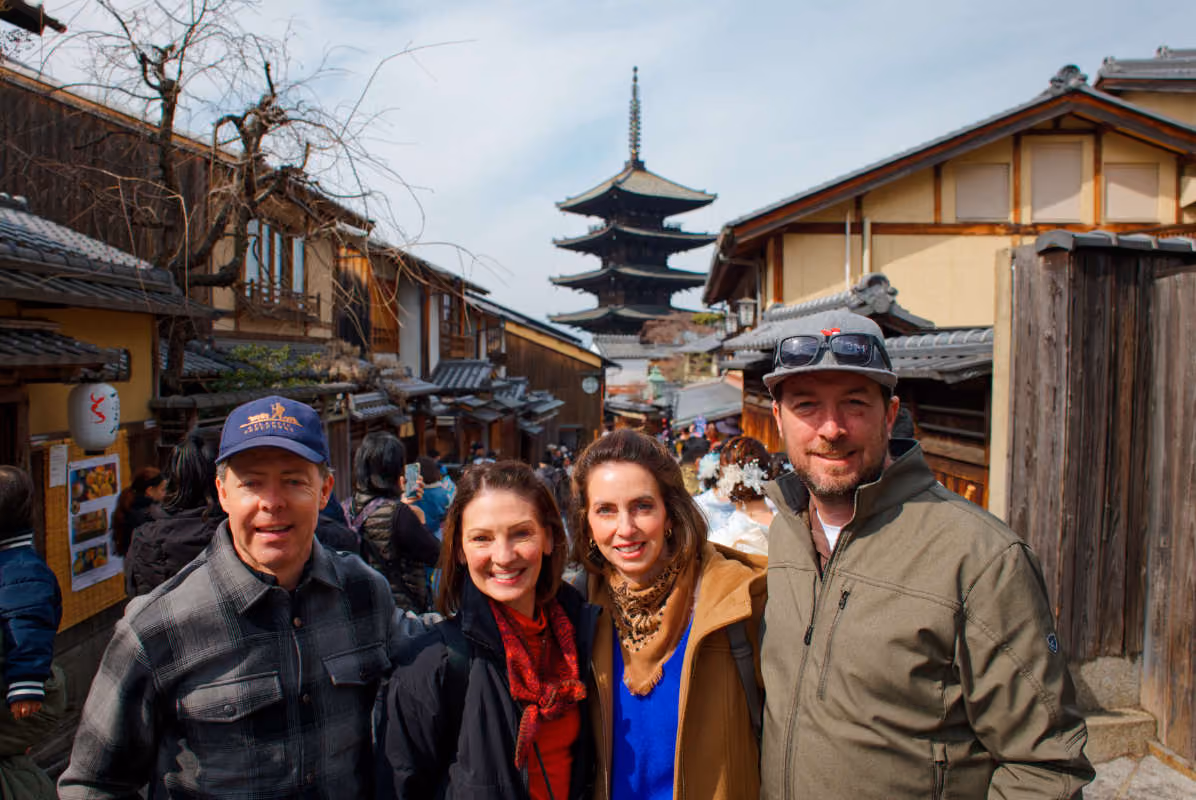 Two men and two women smiling in a traditional Japanese street with a pagoda in the background.