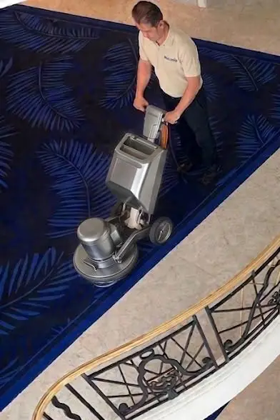 Technicien nettoyant au monobrosse un tapis à motifs