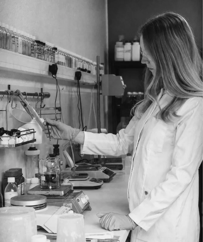 Technicienne en blouse formulant un produit d'entretien en laboratoire