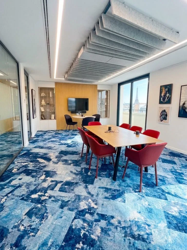 Salle de réunion aux fauteuils rouges sur une moquette bleue à motifs