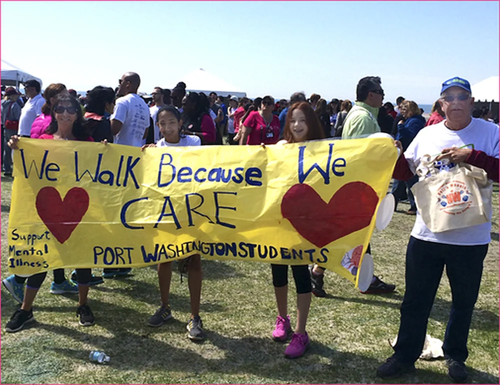 Port Washington students holding a We Walk Because We Care banner supporting mental illness awareness