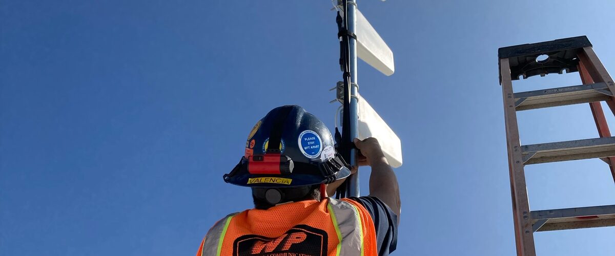 Technician installing a wireless antenna against a blue sky