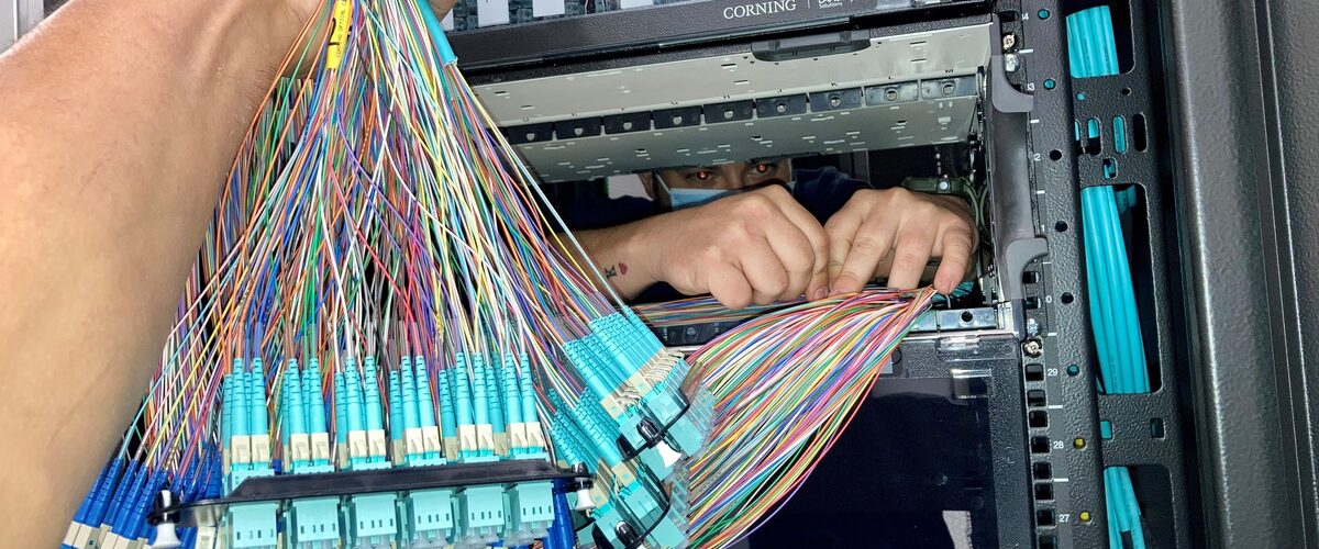 Technician terminating fiber optic cabling in a rack