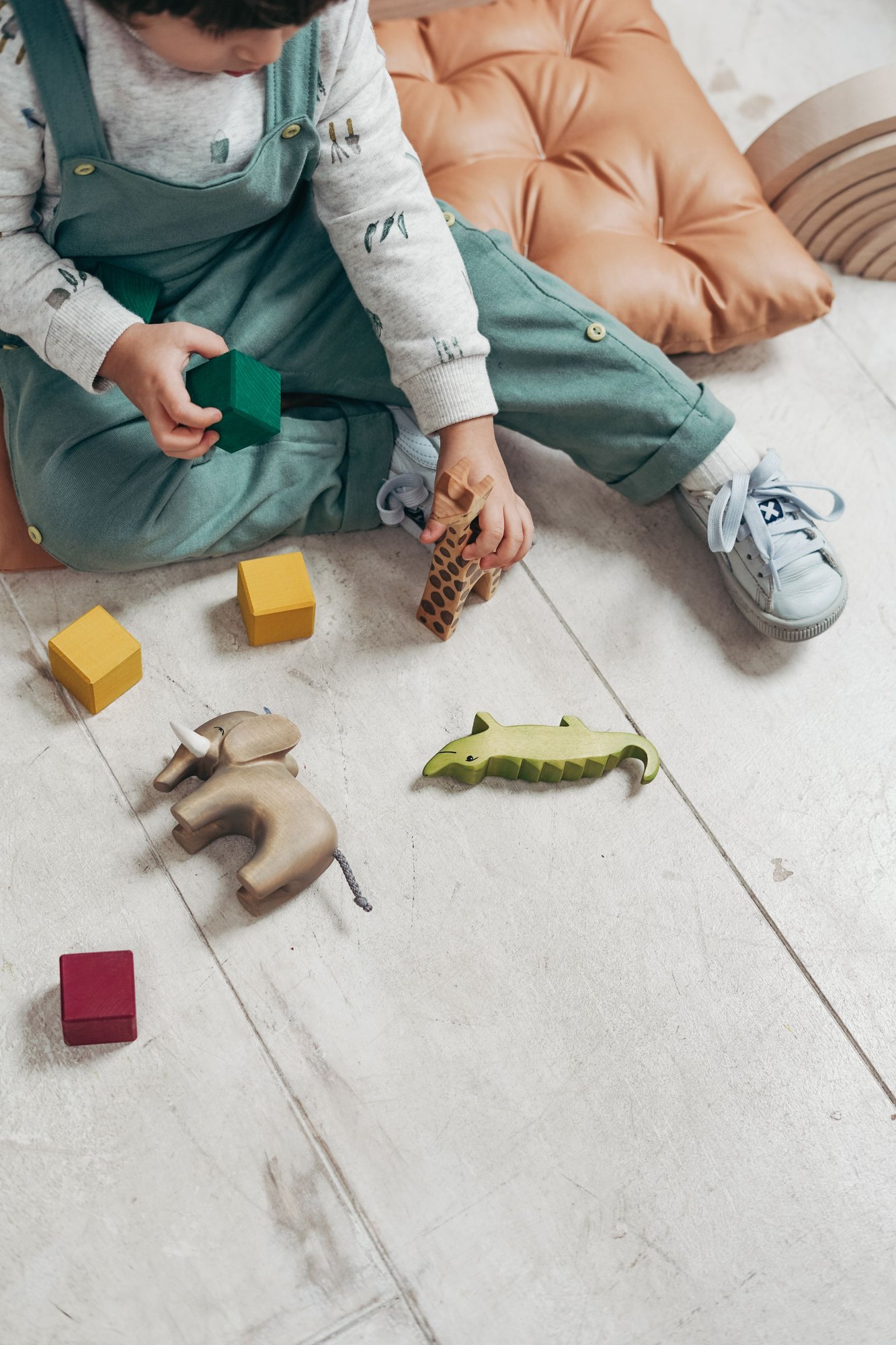 A young child building with wooden blocks on the floor