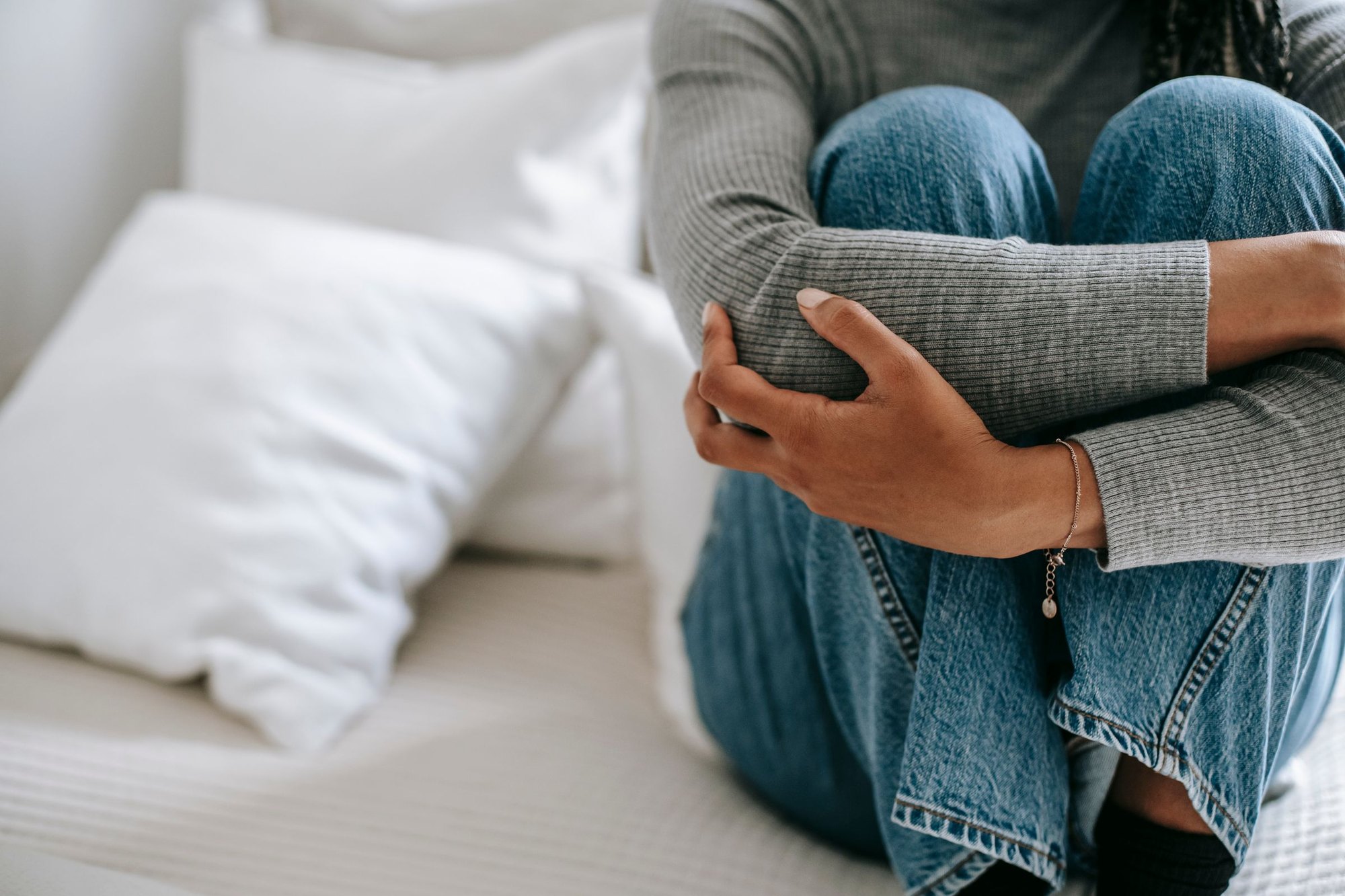 A parent sitting curled up on a sofa at home