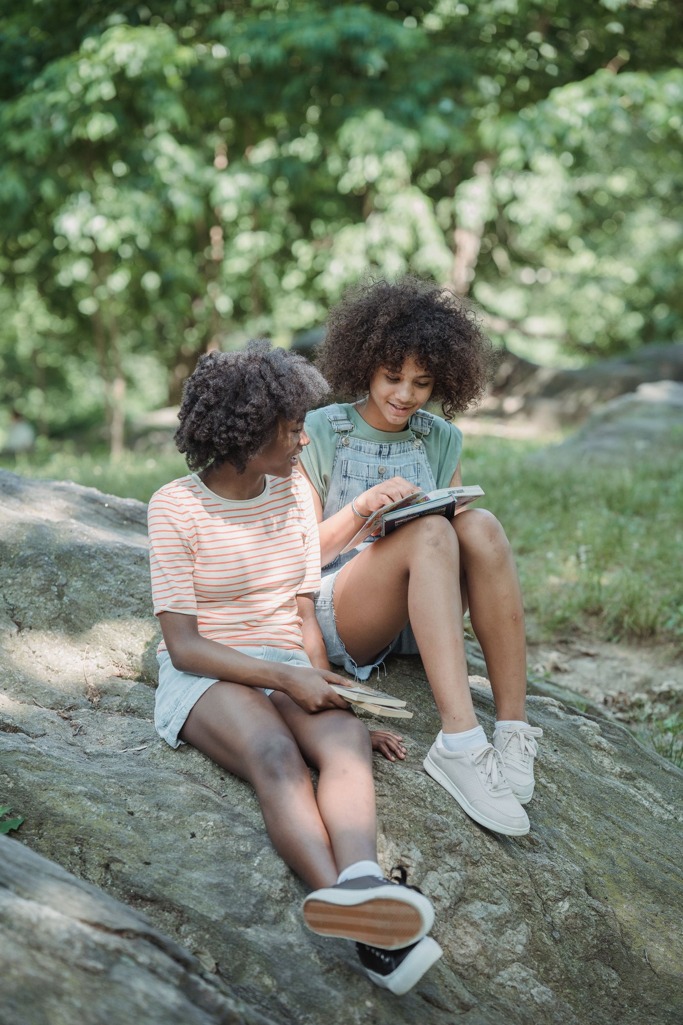 Two teenagers sitting outdoors reading together