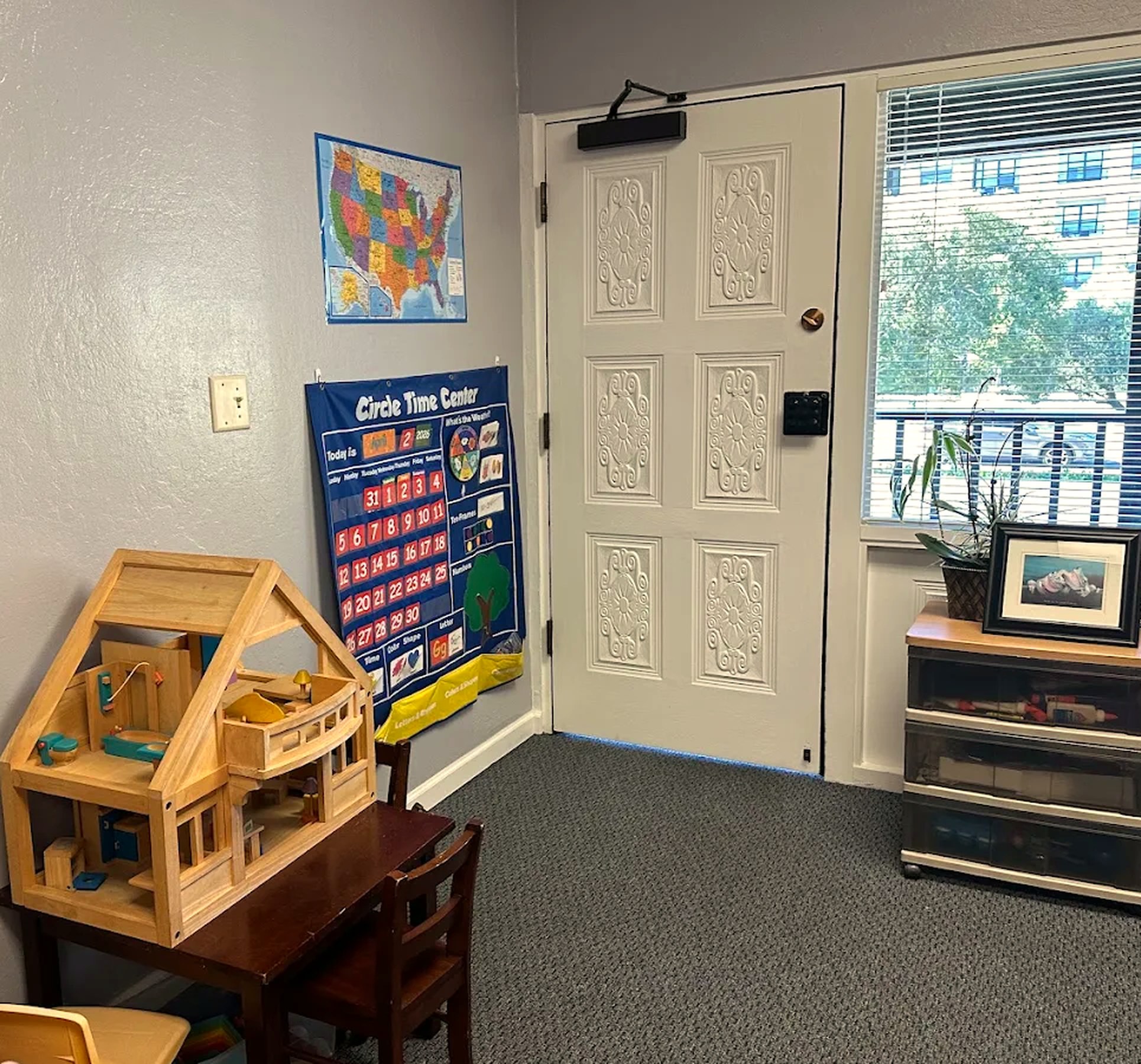 The Redwood City play space, with a wooden dollhouse beside a window