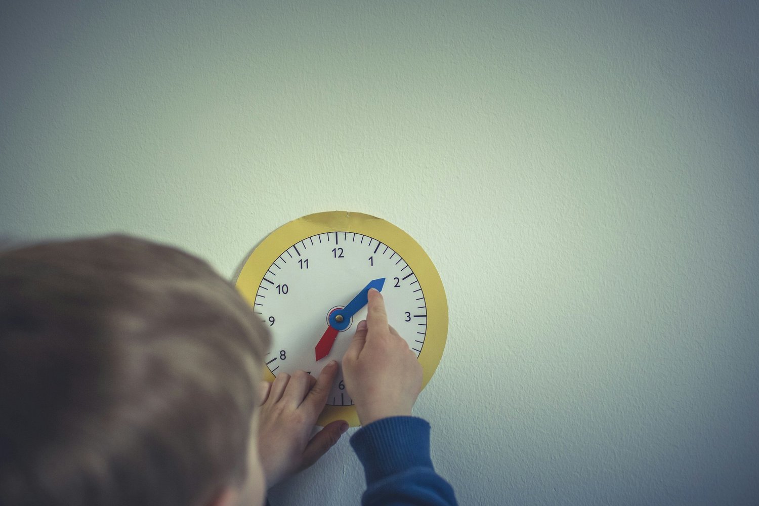 A child drawing a clock face on paper with a pen