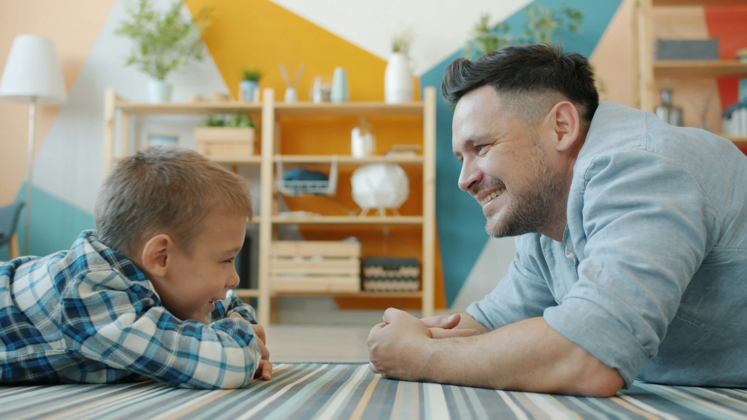 An adult and a child facing each other across a low table in a playroom
