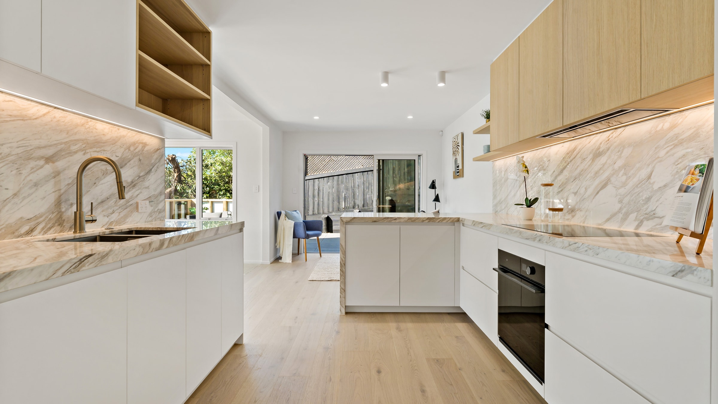 Renovated kitchen with natural stone benchtops and high-end appliances in a Kohimarama reclad home, Auckland
