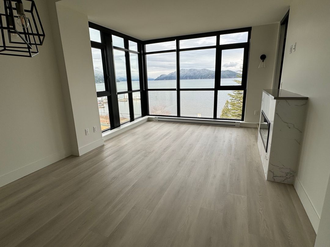 Empty corner room with hardwood floor, a marble fireplace and a sea view