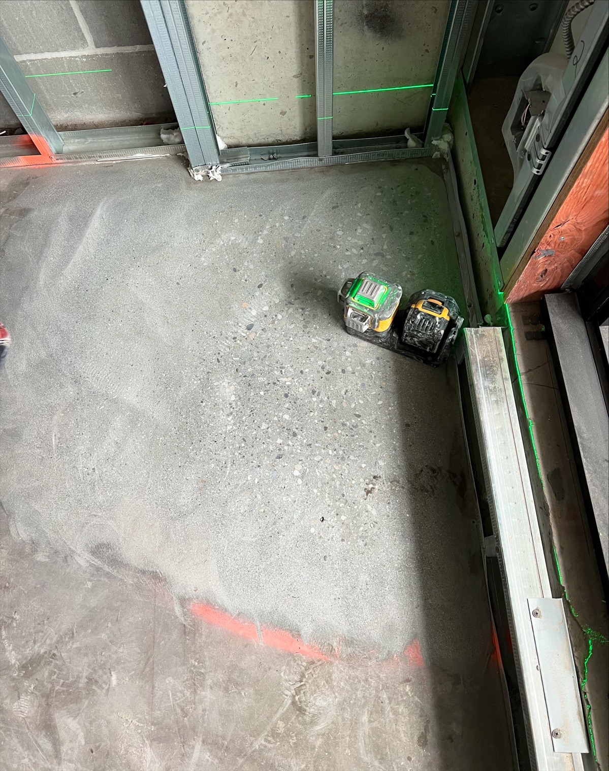 Laser level on the subfloor with green laser lines on the walls