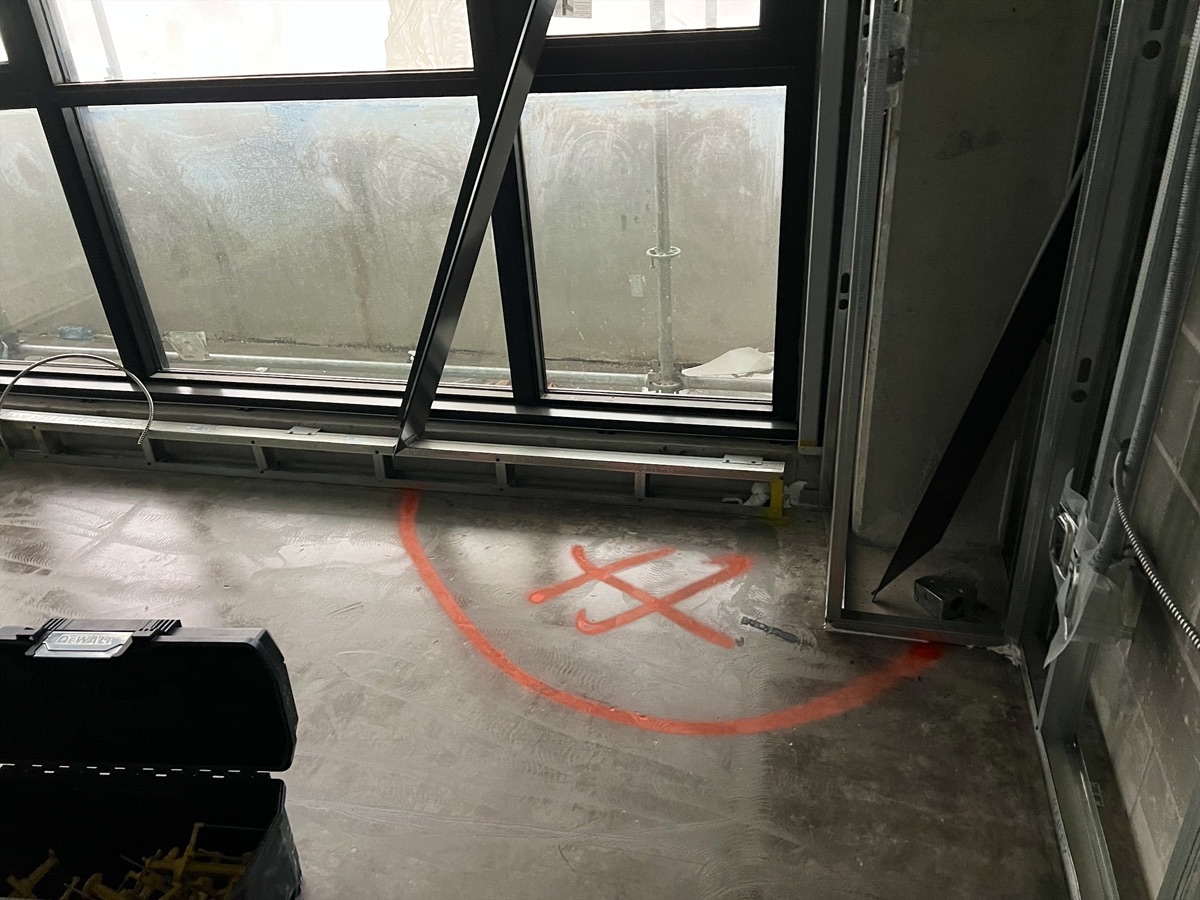 Orange spray circle and cross on the subfloor by a window
