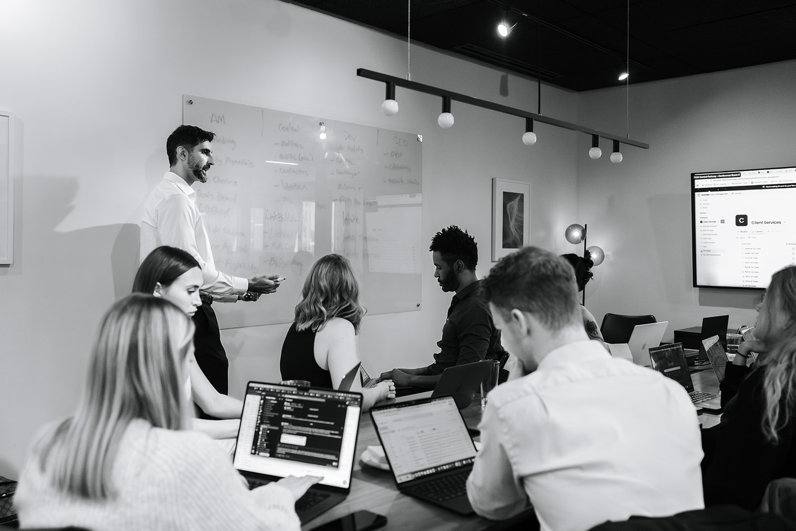 EverSpark team around the conference table in the Atlanta office, agenda on the whiteboard and a remote colleague on the wall screen