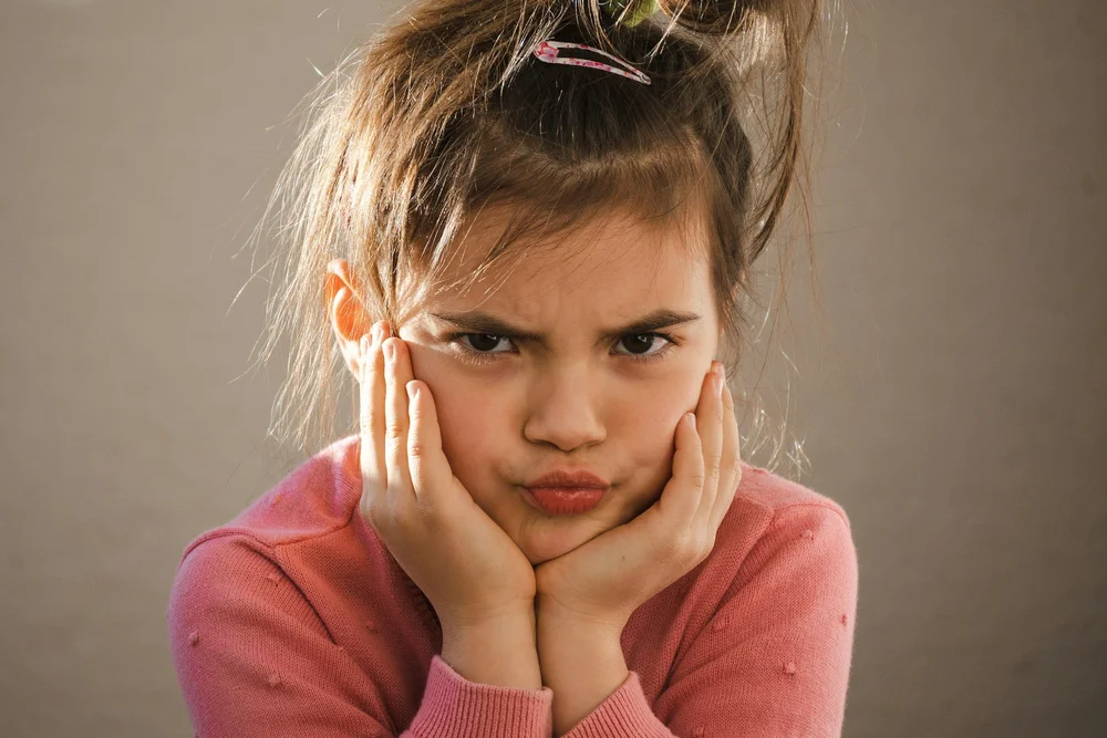 A girl resting her chin in her hands with a fed-up expression