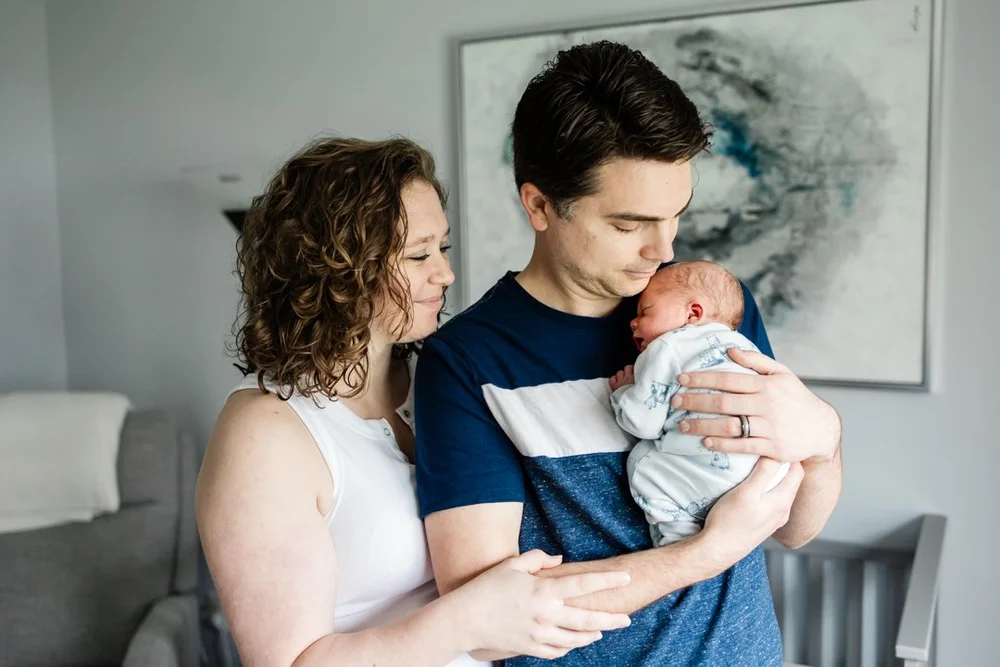 Two parents holding their newborn in a living room