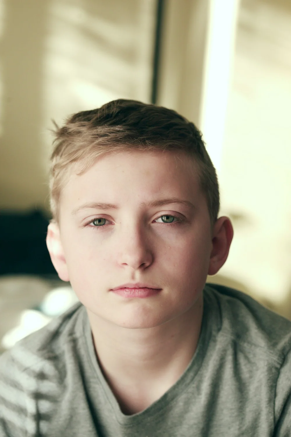 A boy looking at the camera with a quiet, neutral expression