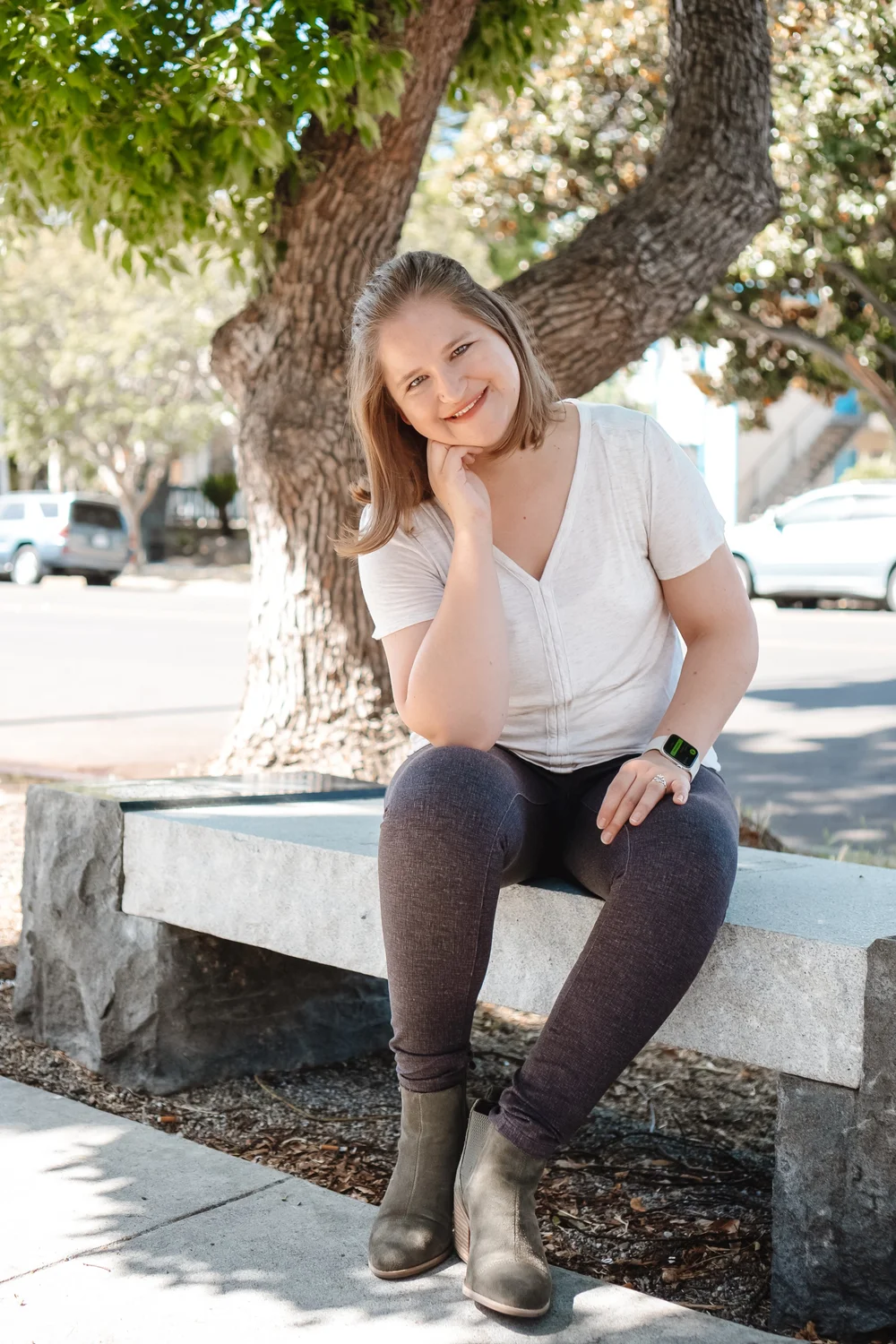 Hannah Ly, LMFT, sitting on a stone bench under a tree