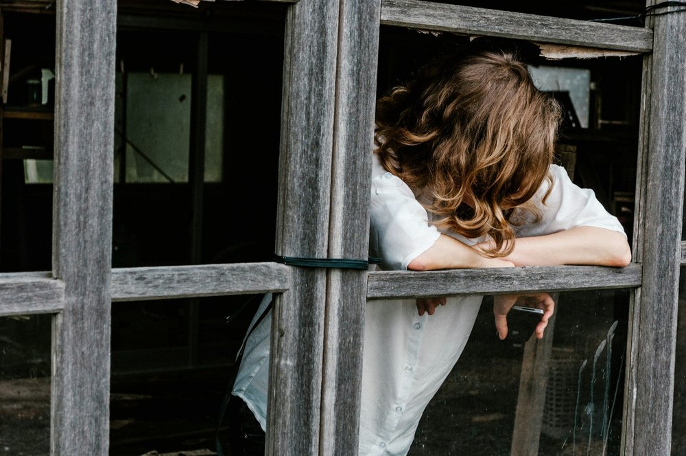 A child leaning out of a weathered wooden window frame