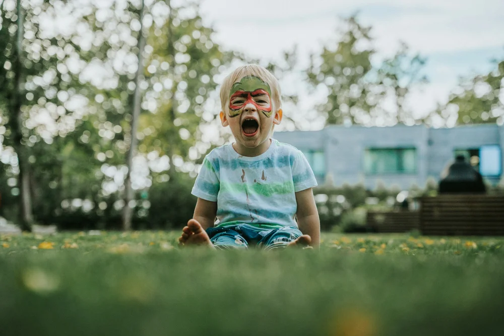 A young child sitting on the grass and crying