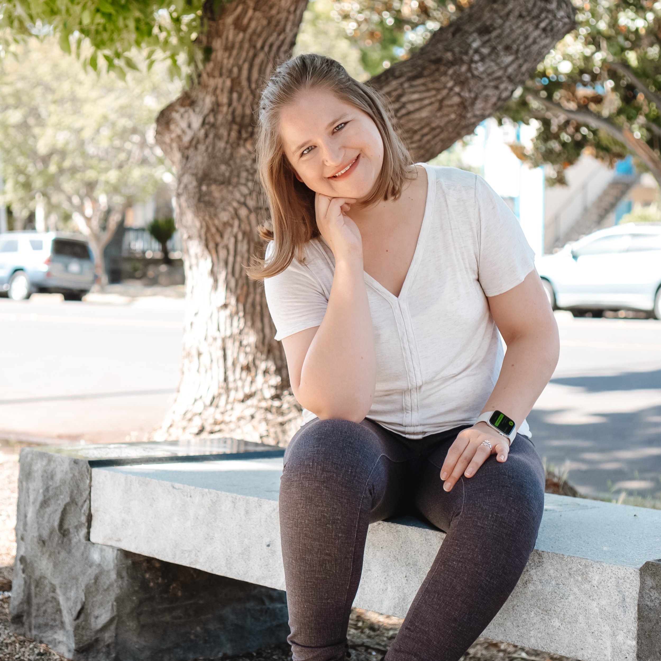 Hannah Ly, LMFT, sitting on a stone bench under a tree