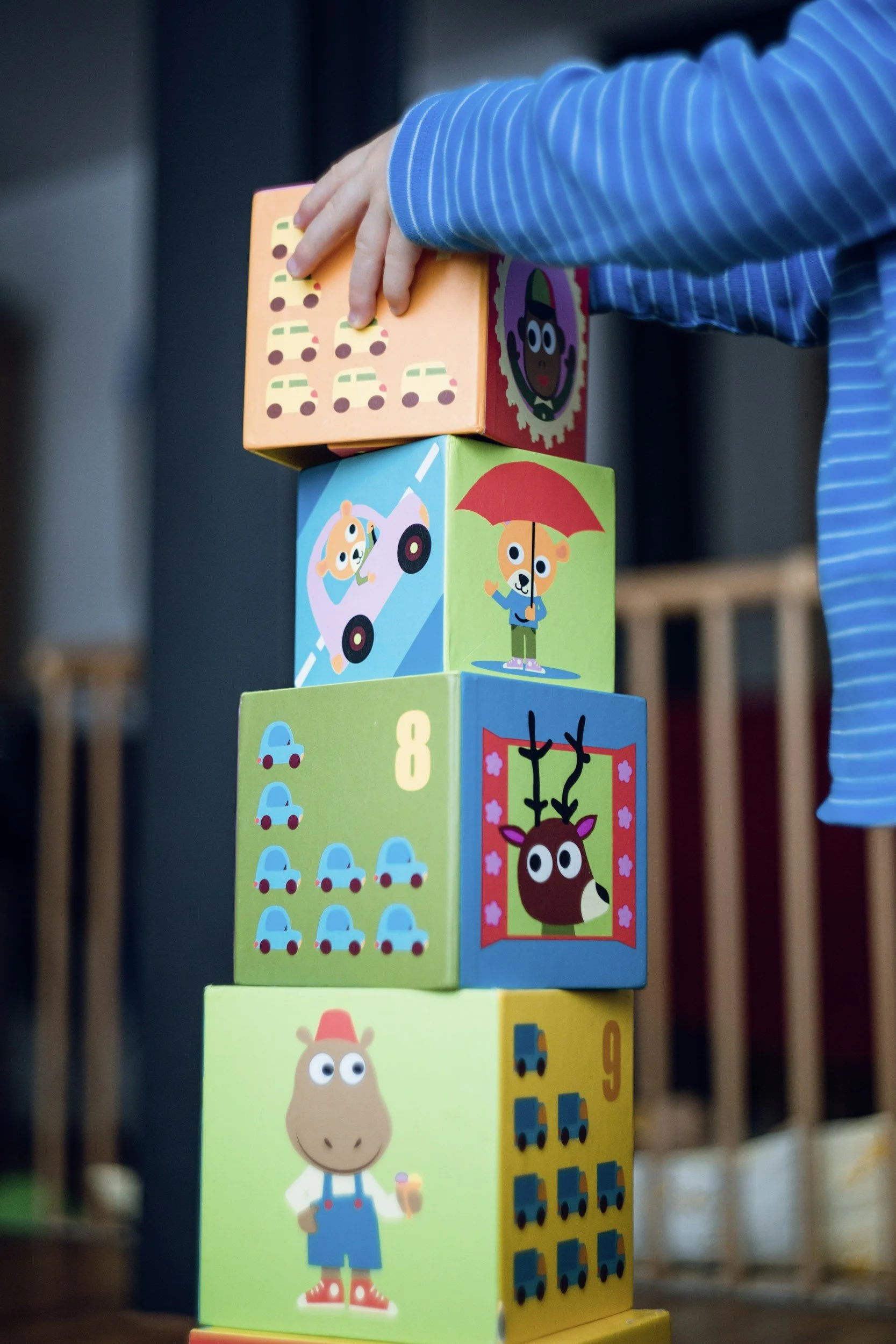 A child stacking printed cardboard blocks into a tower