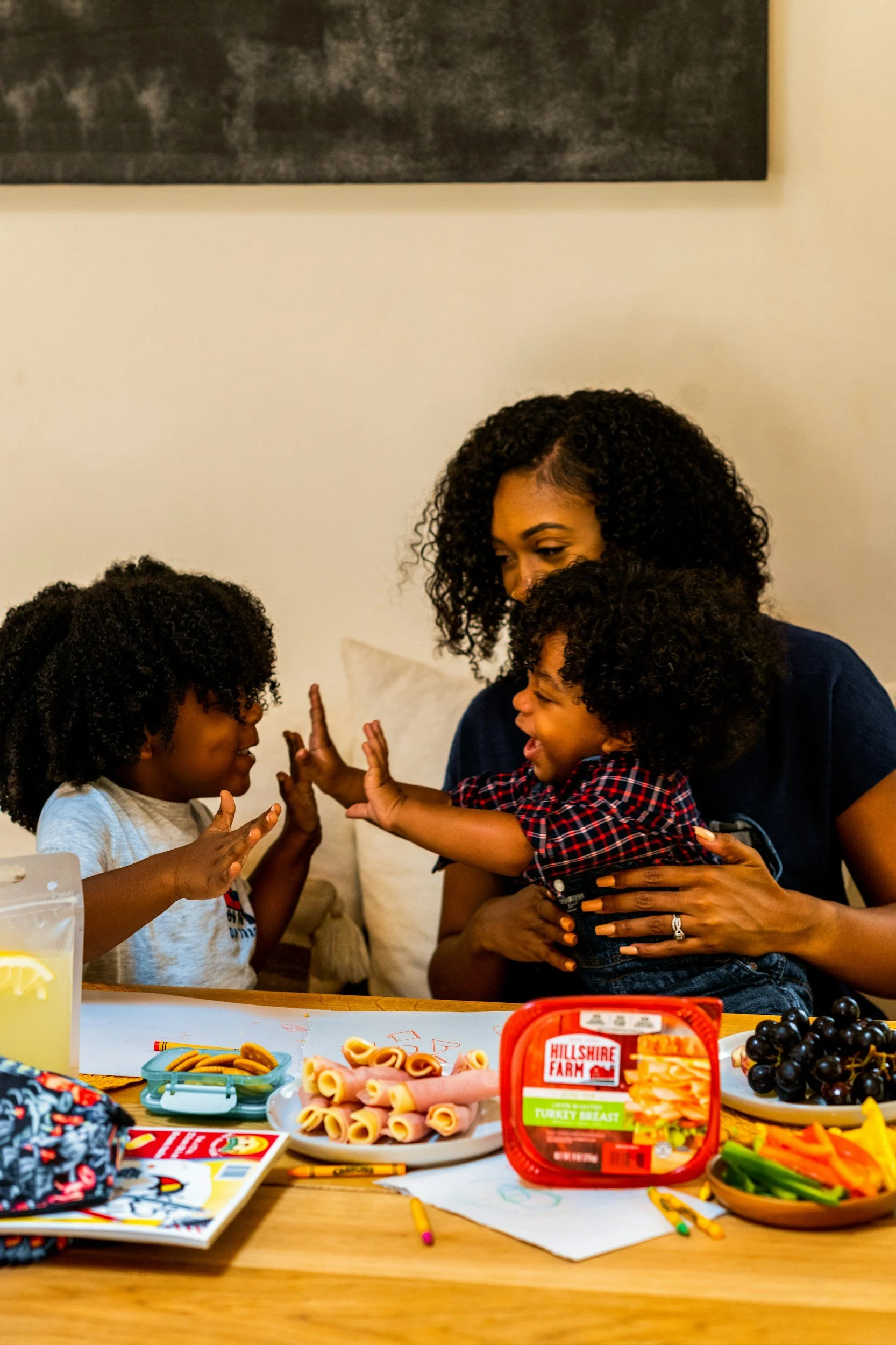 An adult and two children high-fiving across a table set with food